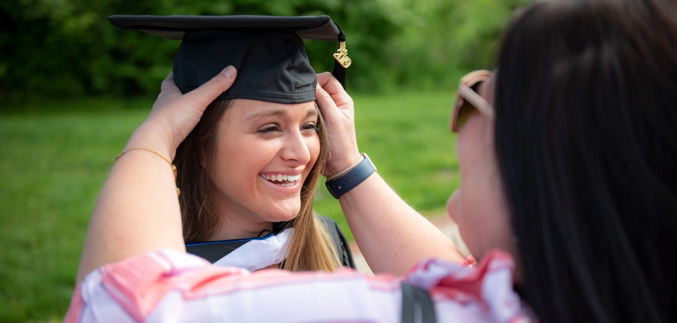 Mother adjusting student's graduation cap