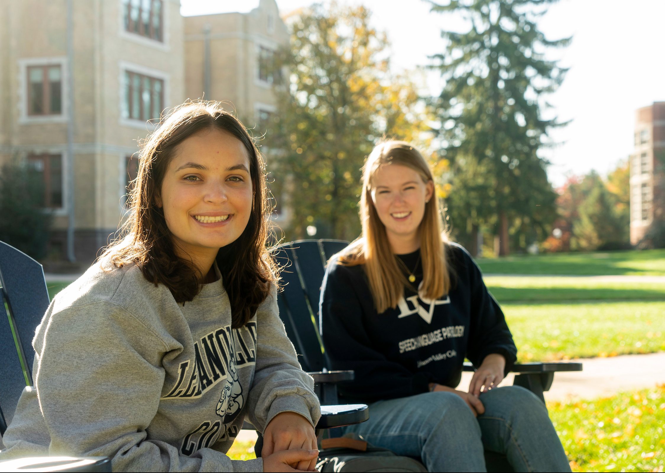 Students smile while sitting on campus quad