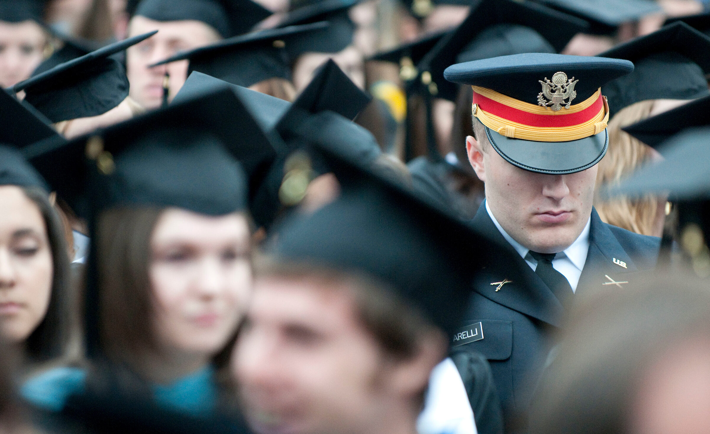 Military member stands in crowd at commencement ceremony