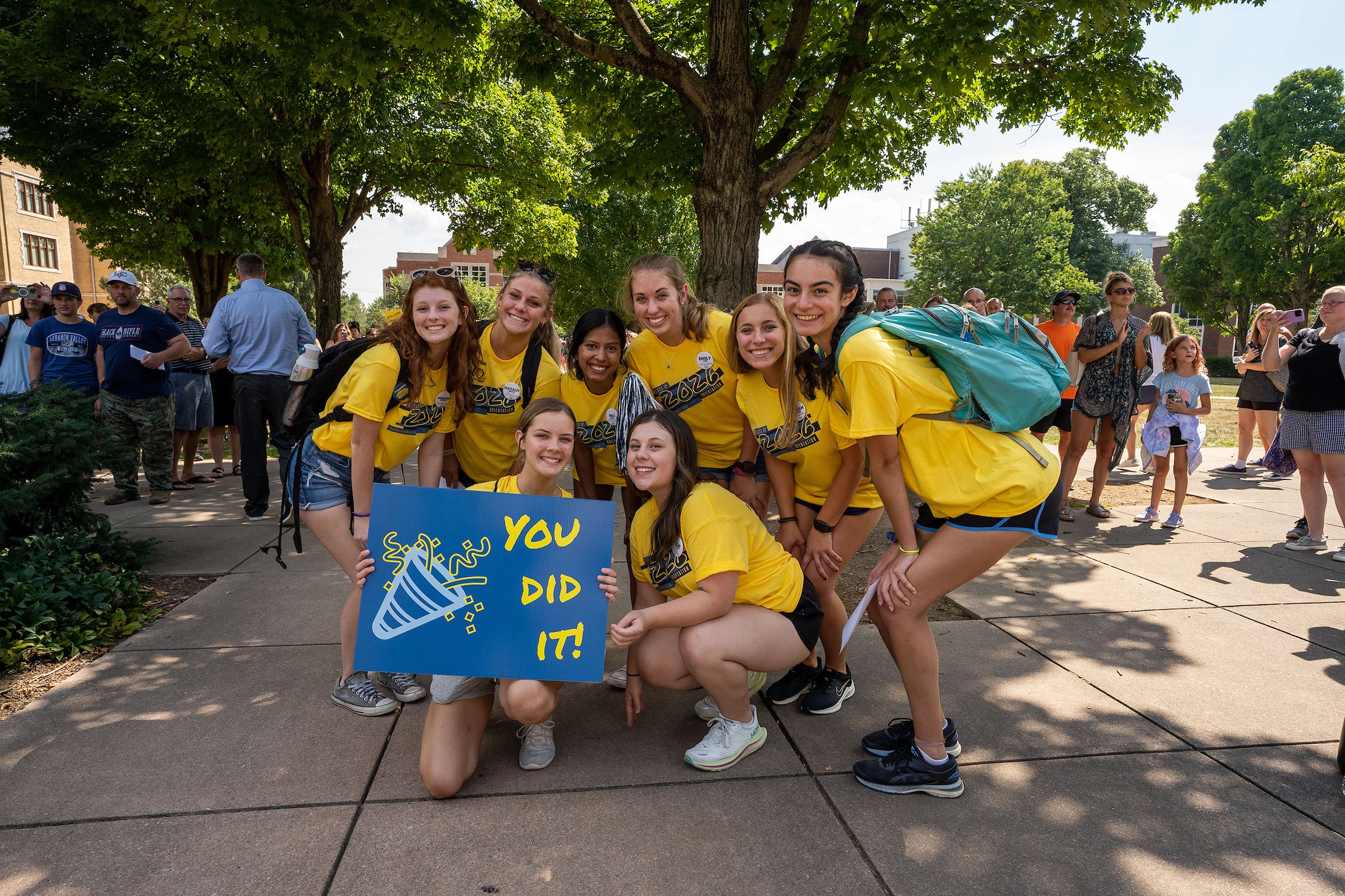 Students pose with sign that says you did it for school spirit in bright yellow shirts