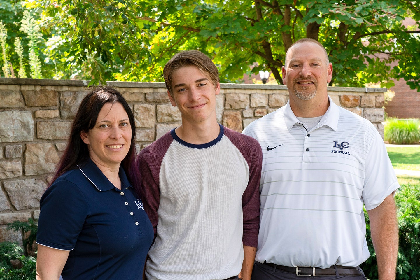 Student smiling with his parents in shirts with the LVC logo.