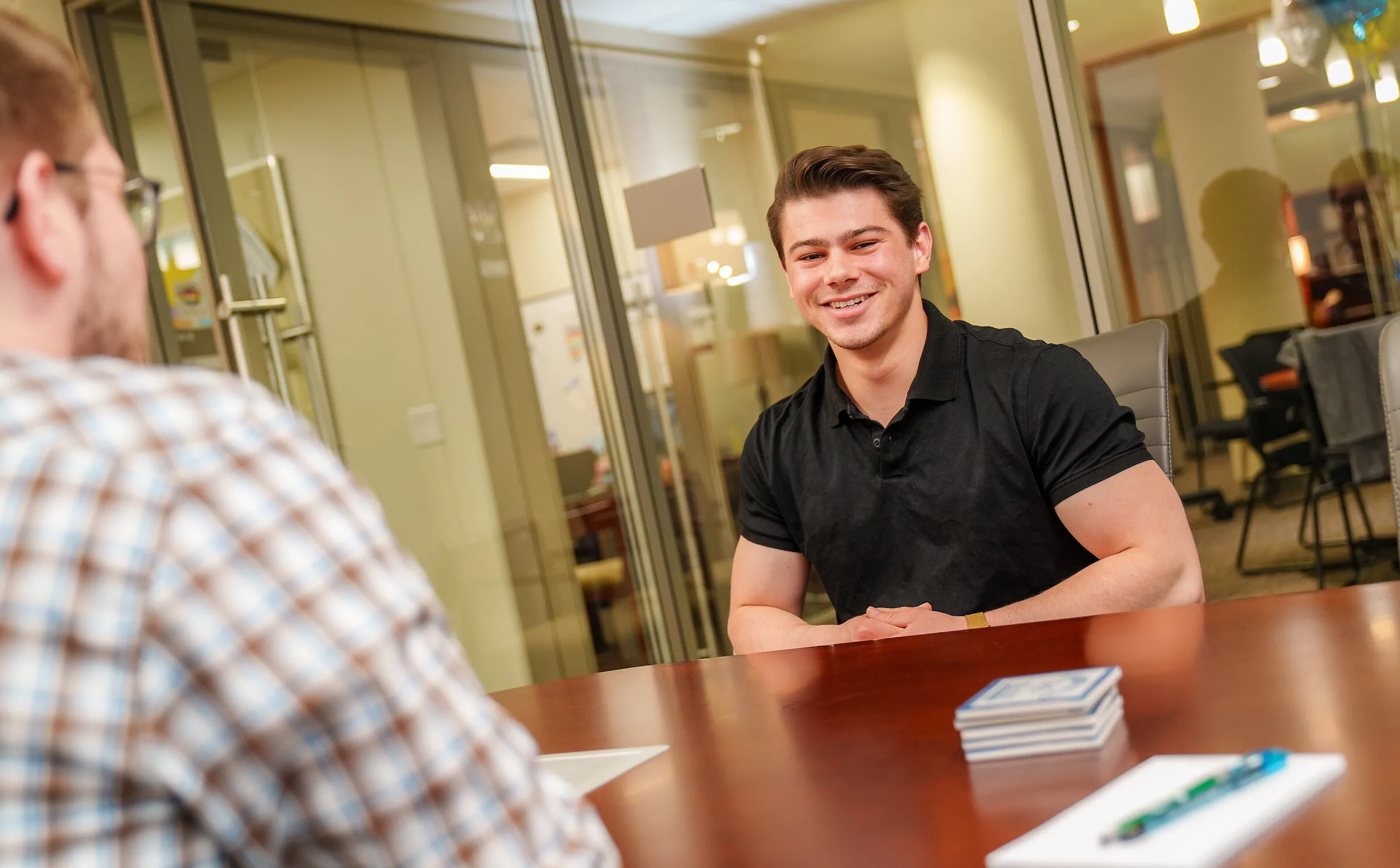 Student and professional talking at a desk.