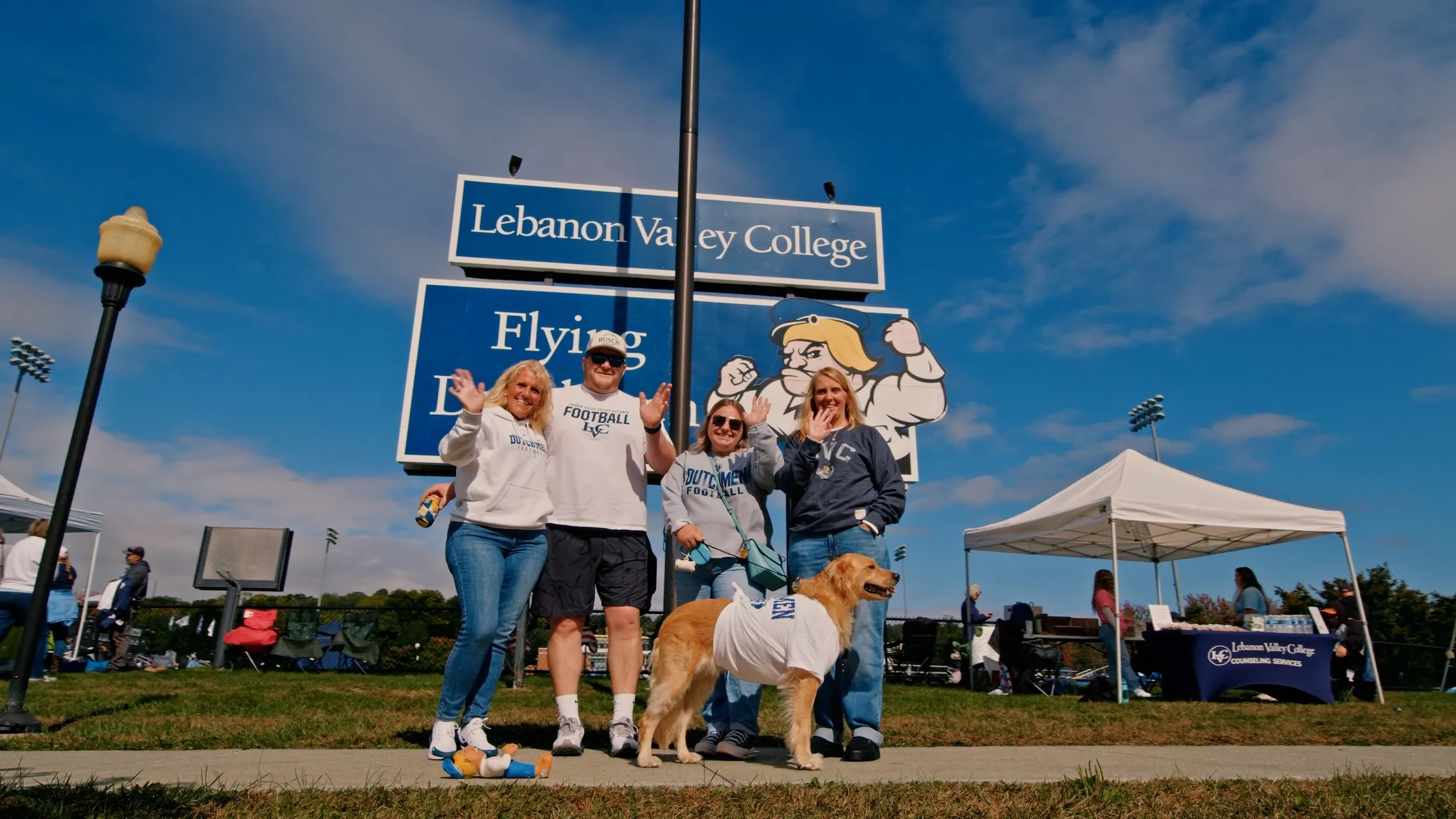Family with dog waves at Homecoming