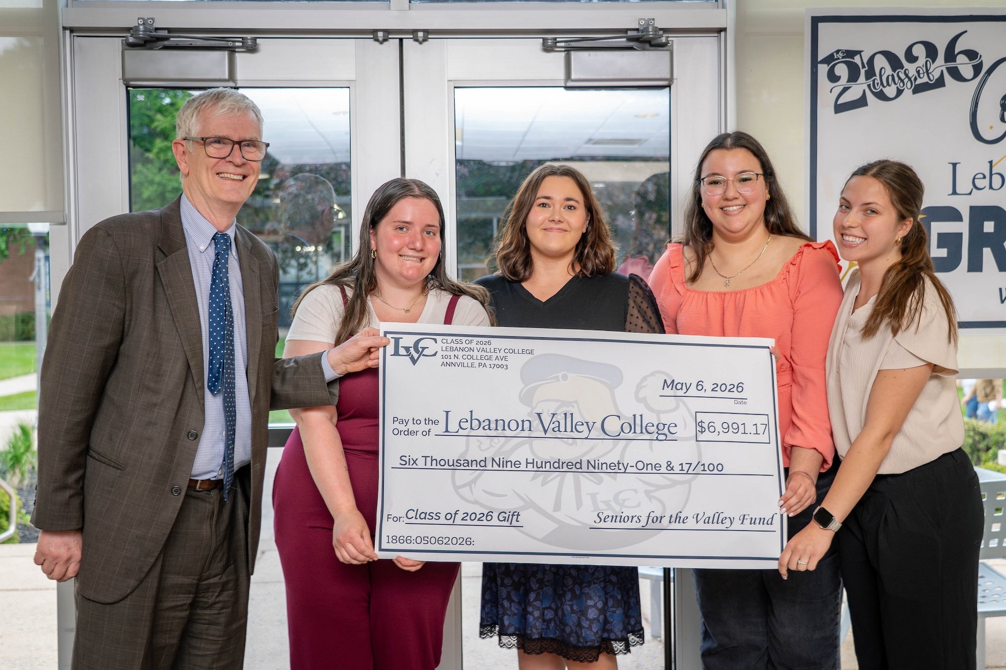 Through their efforts, the Class of 2026 raised $6,991.17. Seniors and President MacLaren pose with large check.