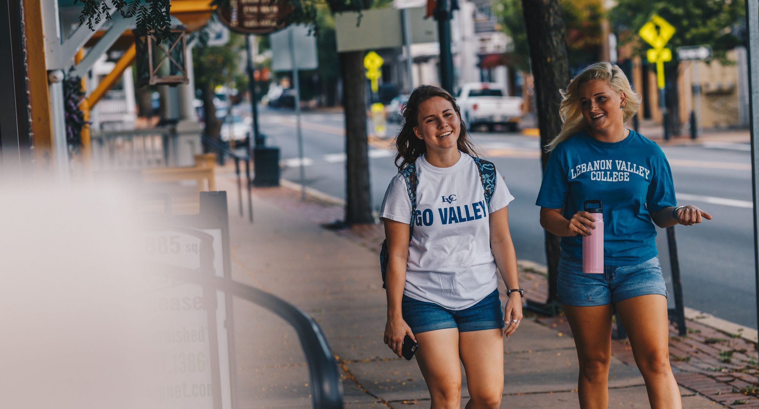 Two students walking down a sidewalk.