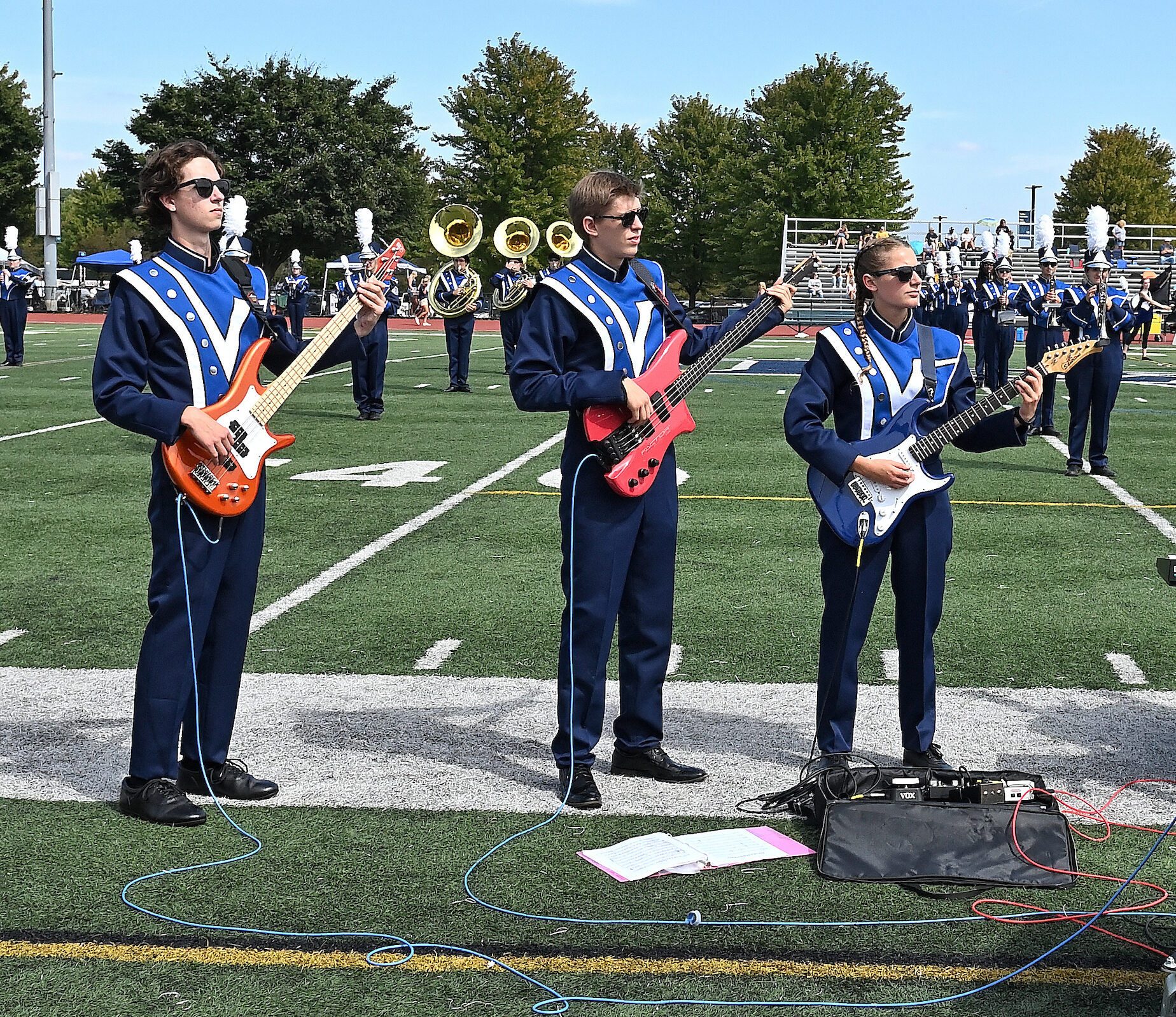 Members of marching band hold guitars on field