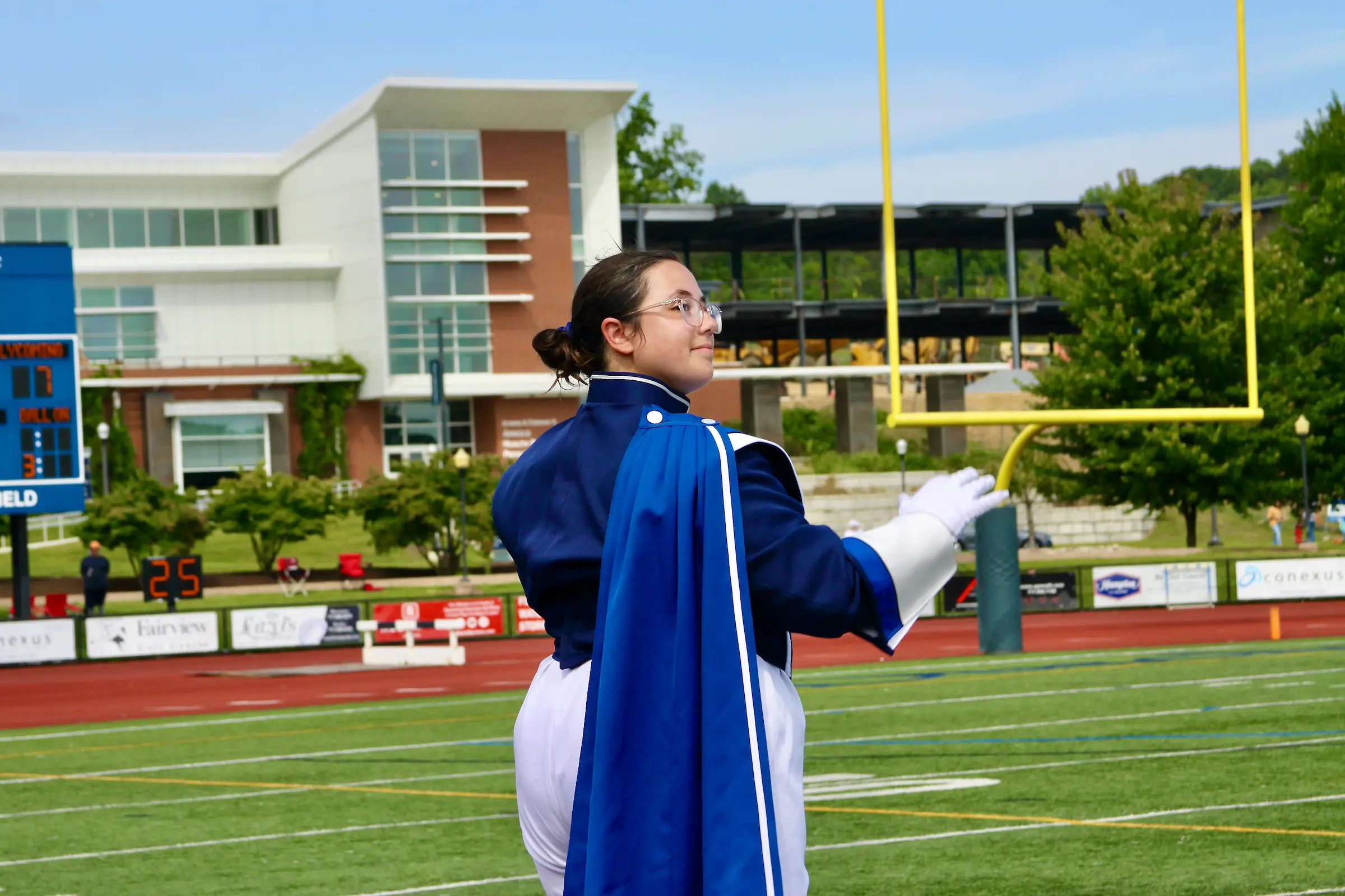 Marching band conductor stands on football field