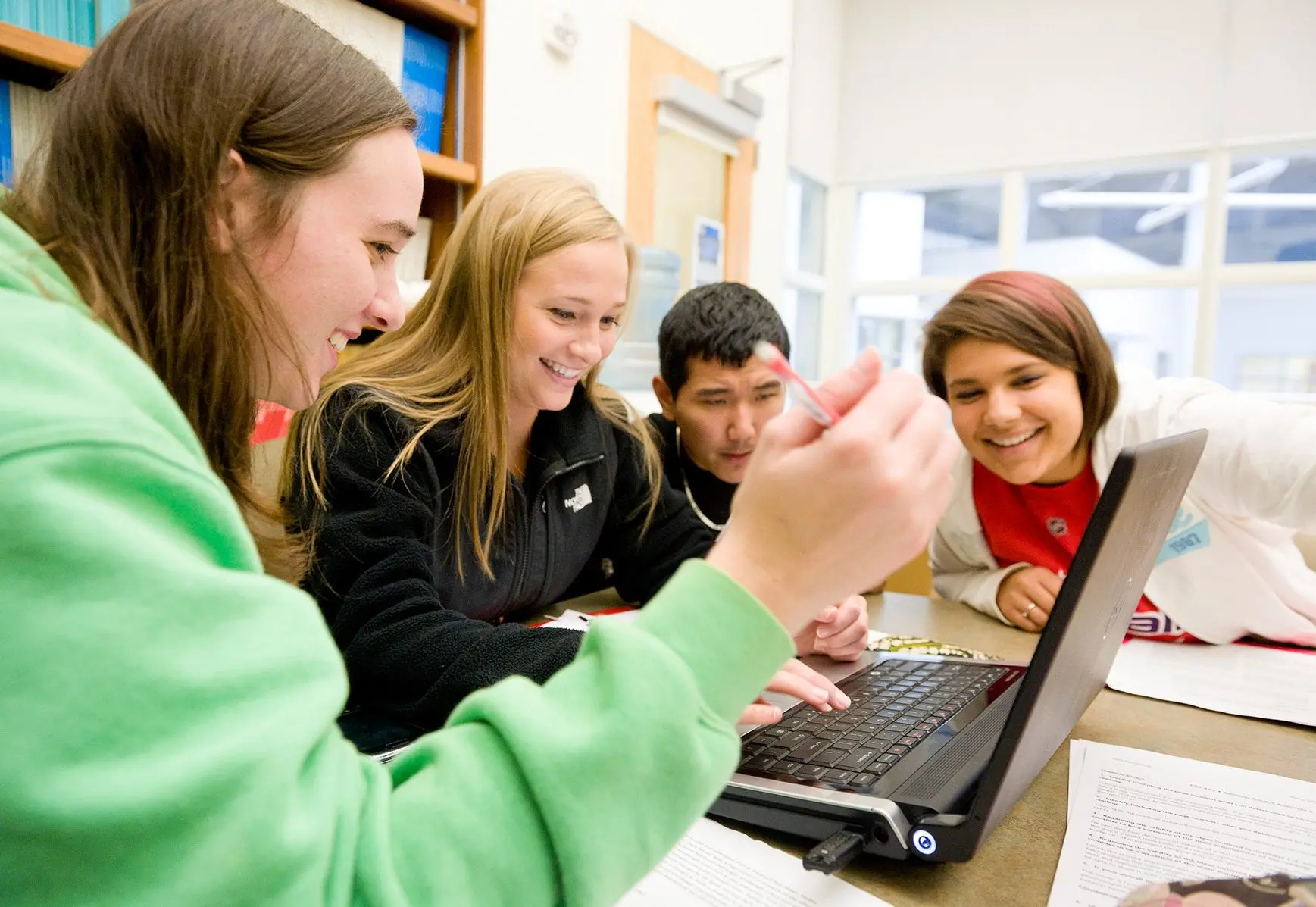 Students gathered around a laptop while studying.