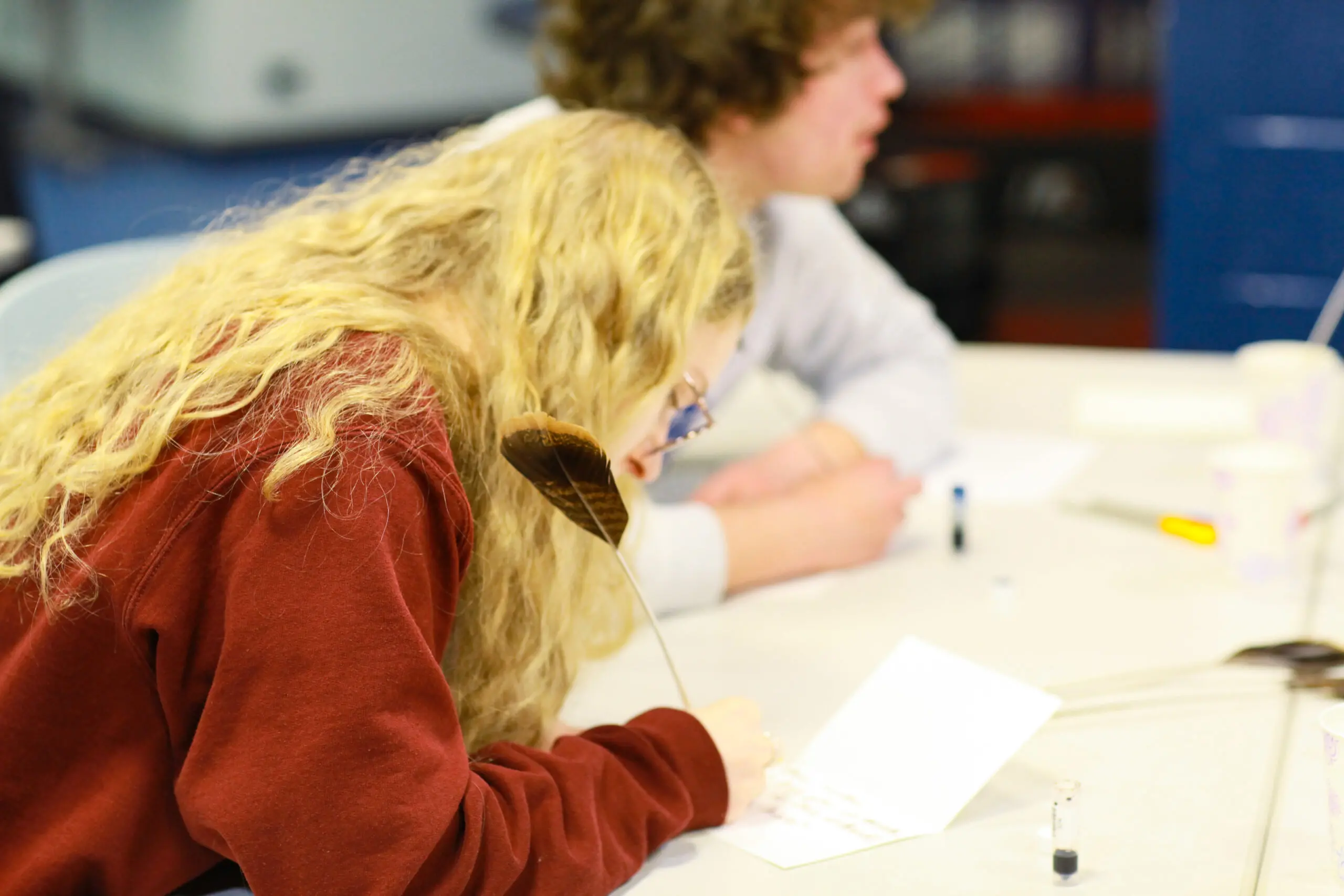 Student writes with quill during medieval crafts workshop