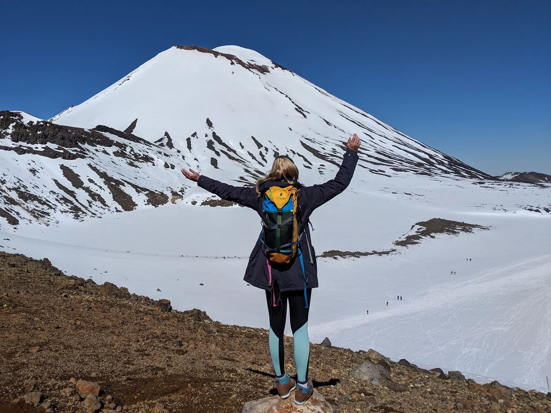 Student studying abroad in front of a large snowy mountain.