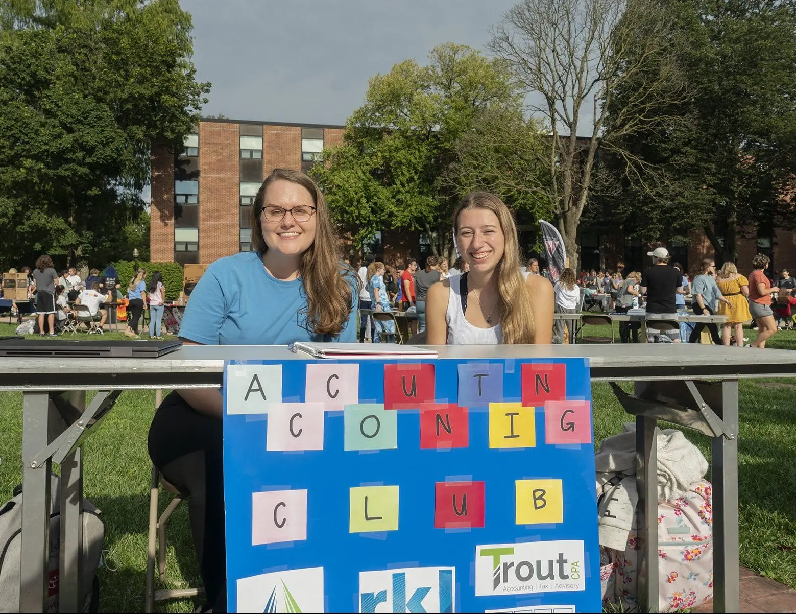 Two students sitting behind the accounting boot at student engagement fair
