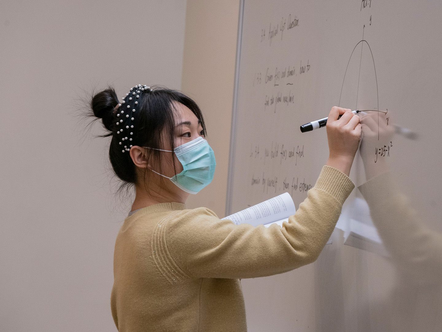 Woman actuarial science professor writing on whiteboard