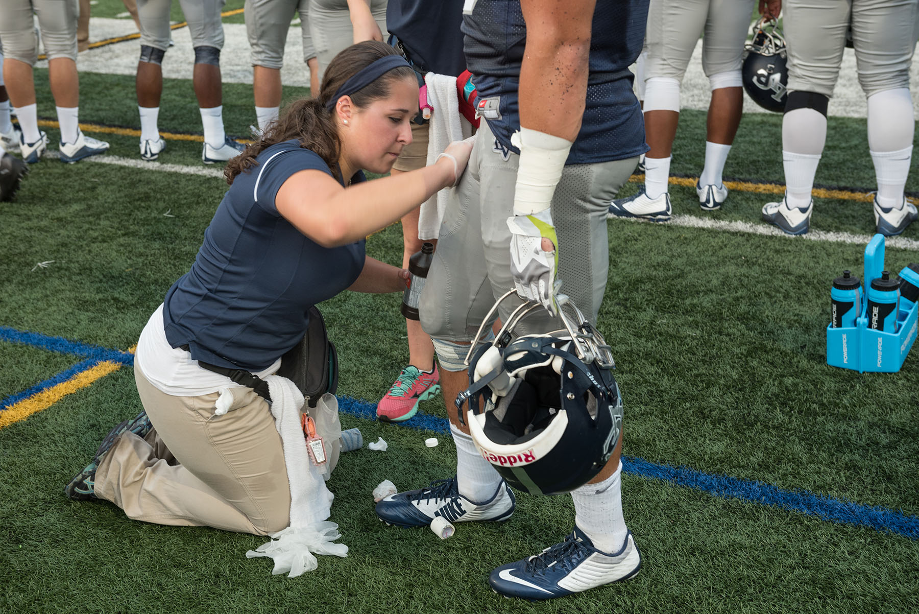 Student athletic trainer works on football player