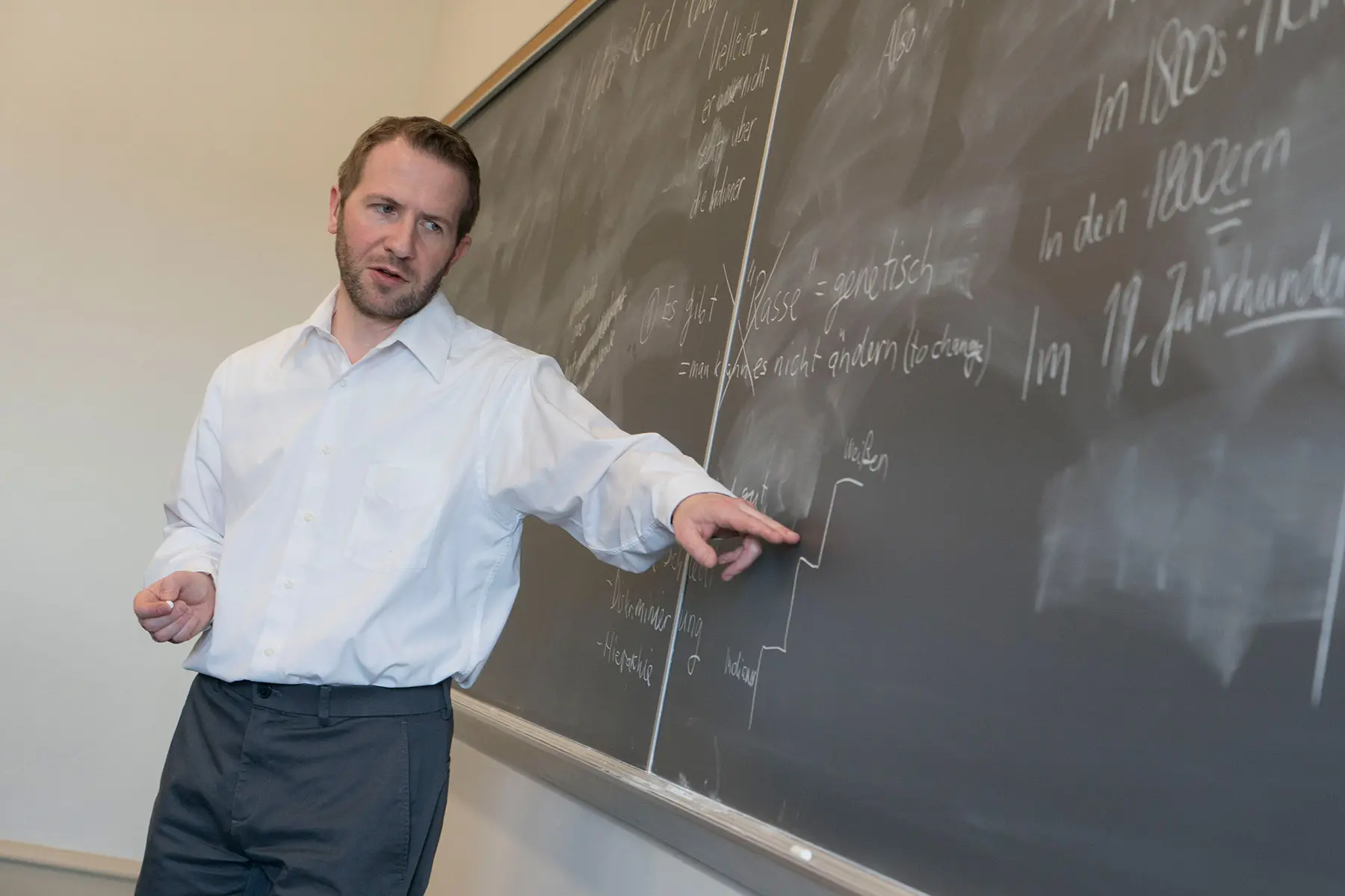 Professor pointing to German sentence on chalkboard