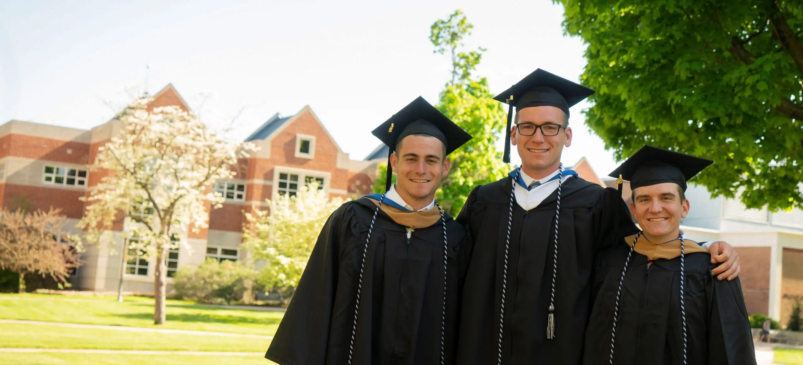 Students posing in caps and gowns on LVC campus lawn