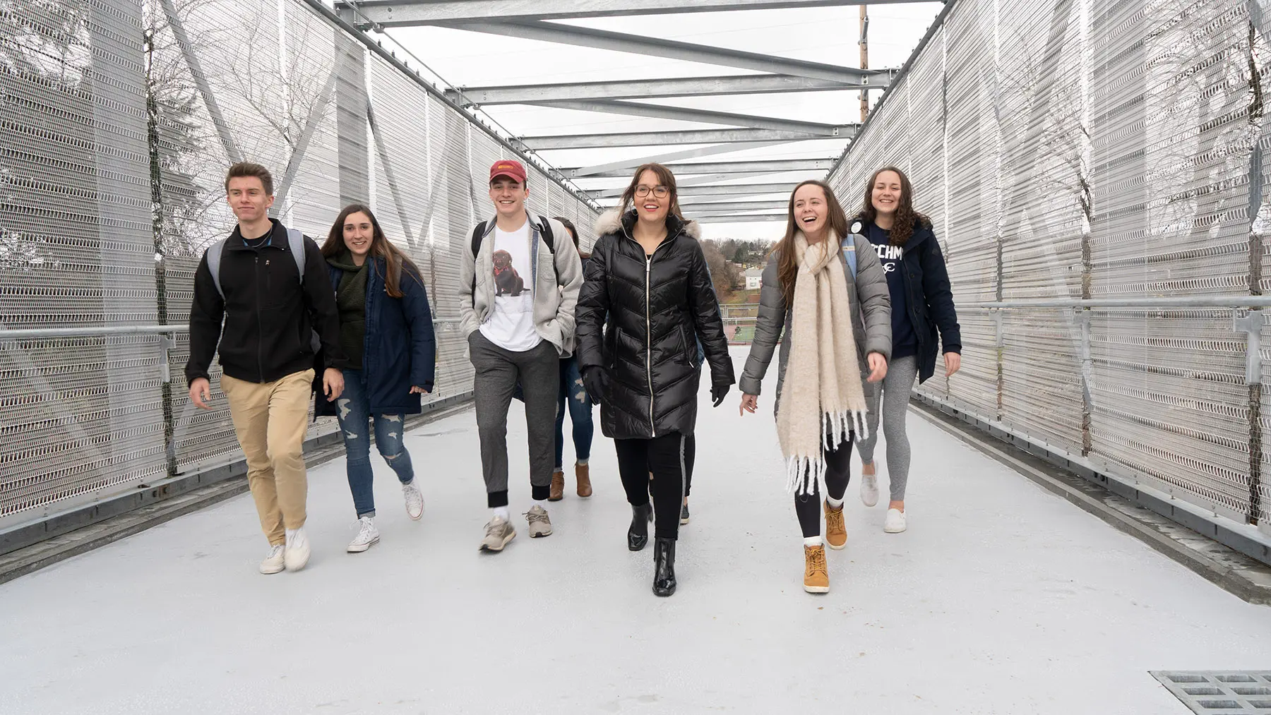 Smiling students crossing the campus bridge
