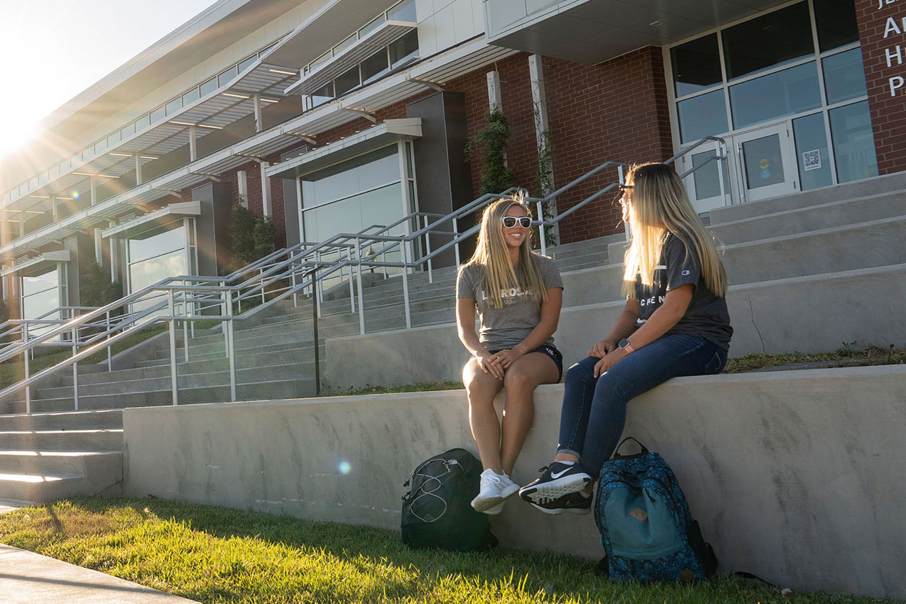 Two students sitting outside a campus building chatting
