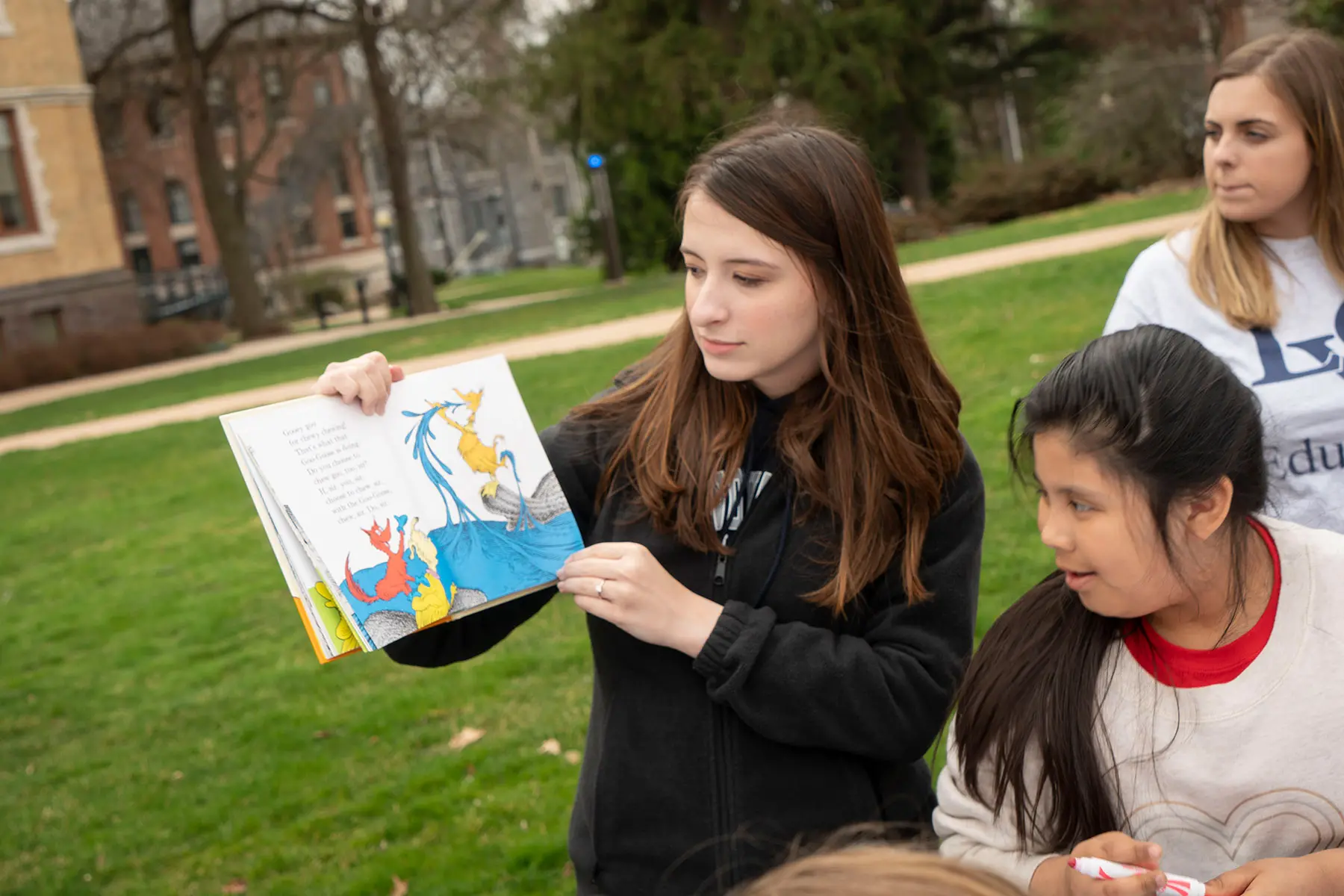 Student reading picture book to children