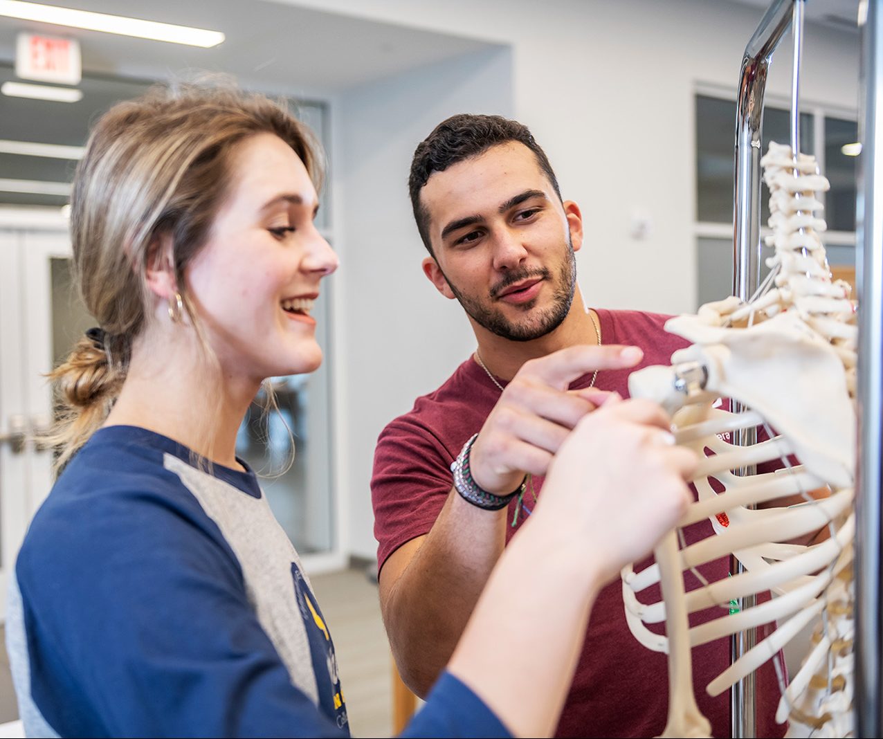 Two students examining a medical skeleton
