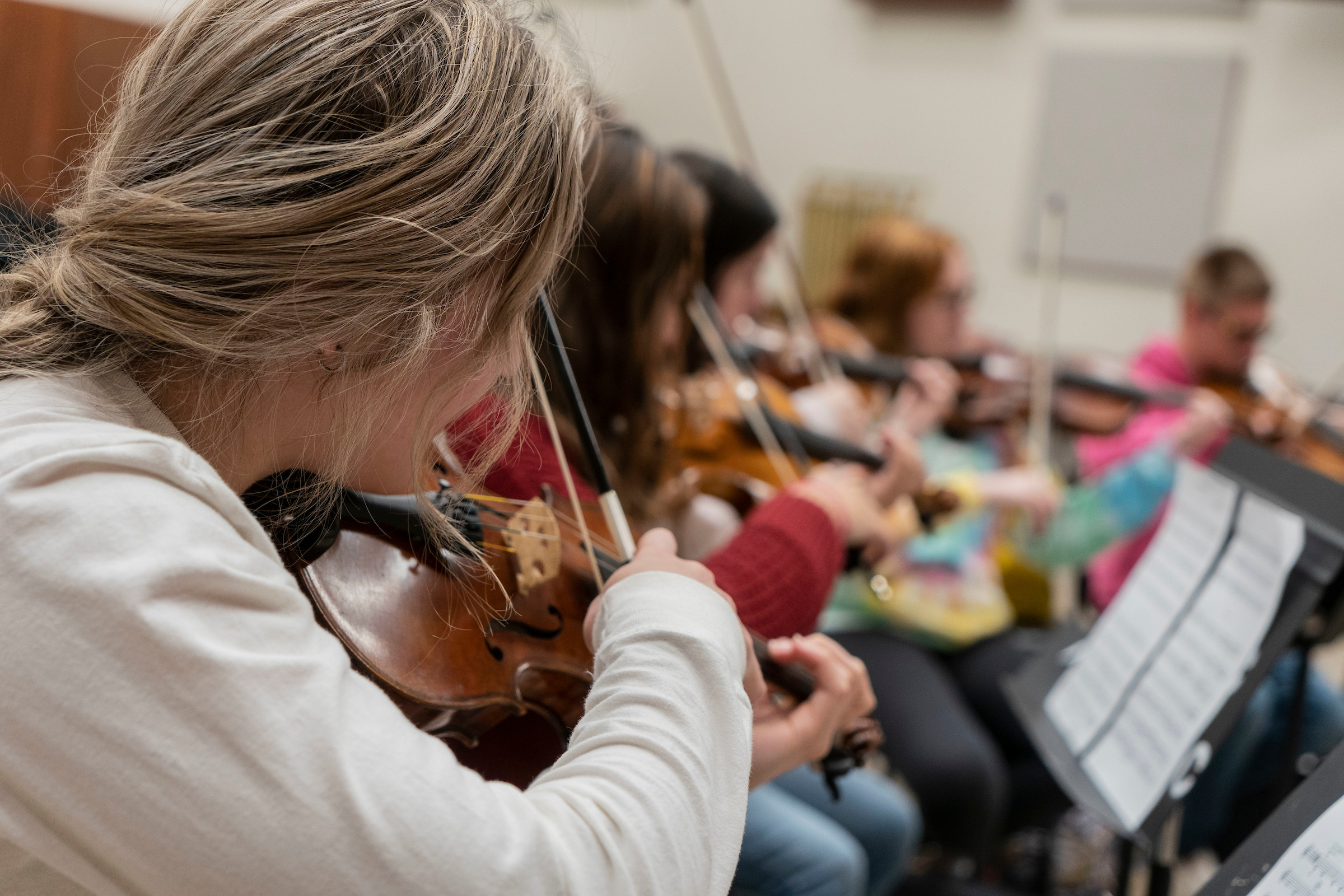 Orchestra students play string instruments in studio