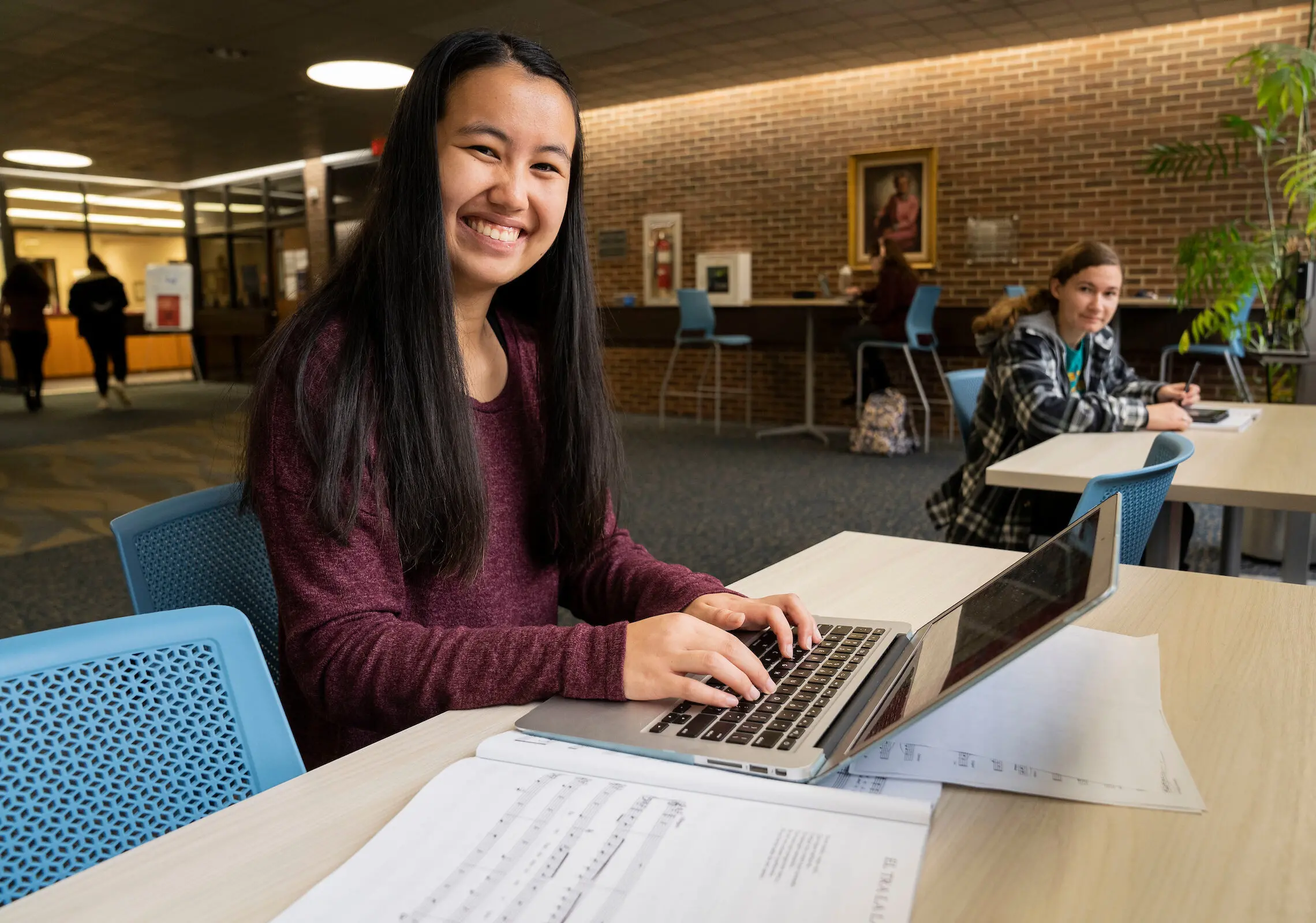 Music student smiles while working on laptop