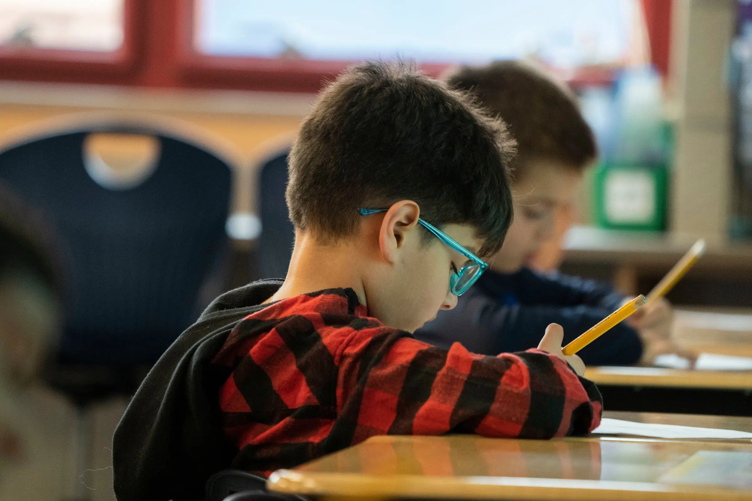 Elementary student sits at desk with pencil