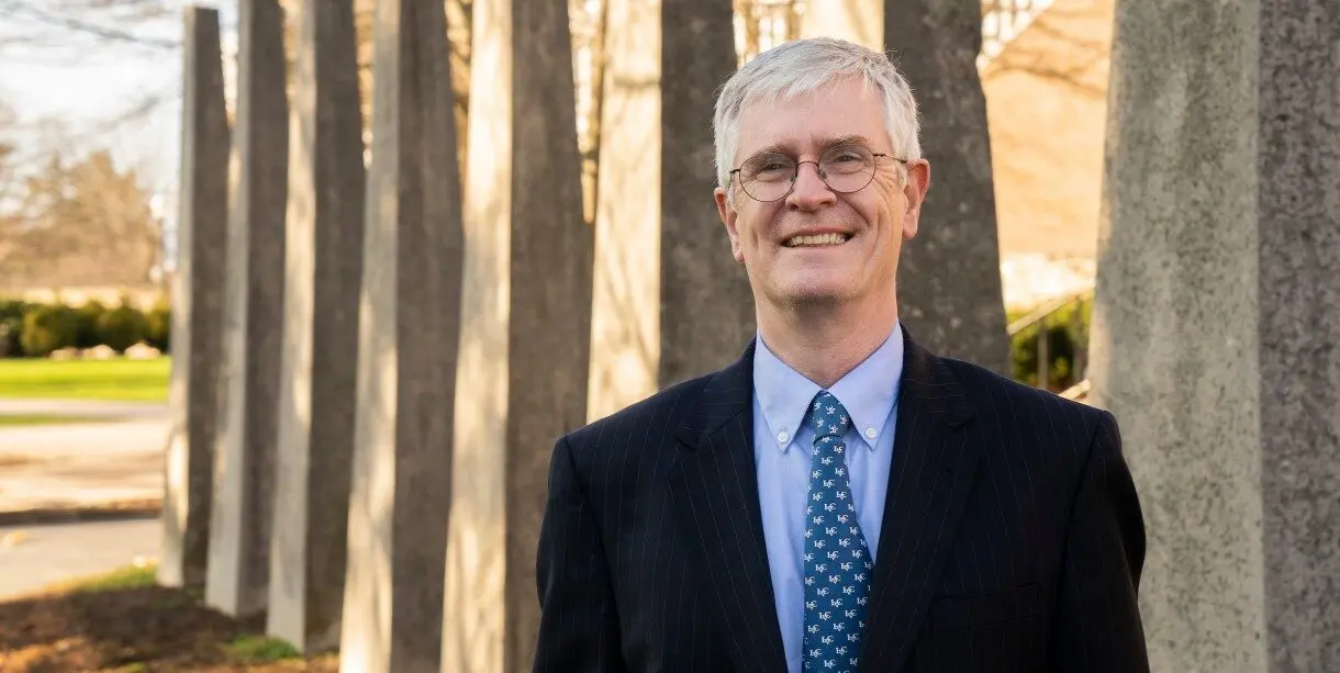 President James MacLaren posing in front of rows of trees