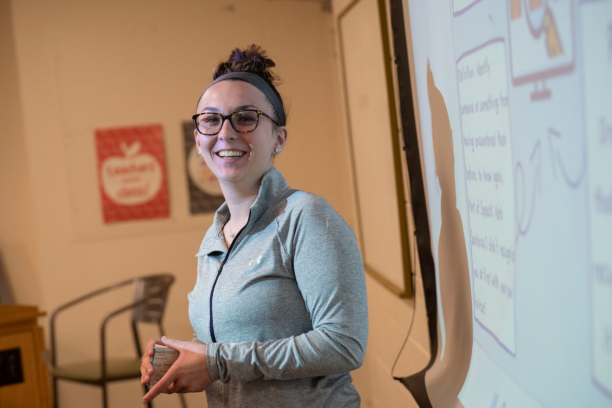 LVC student smiles by projector screen in education classroom