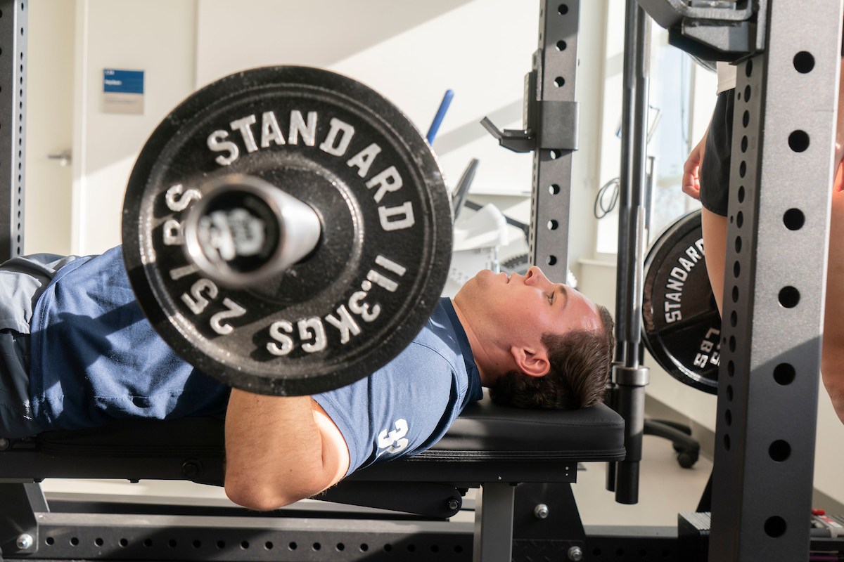 Exercise science student bench presses weights
