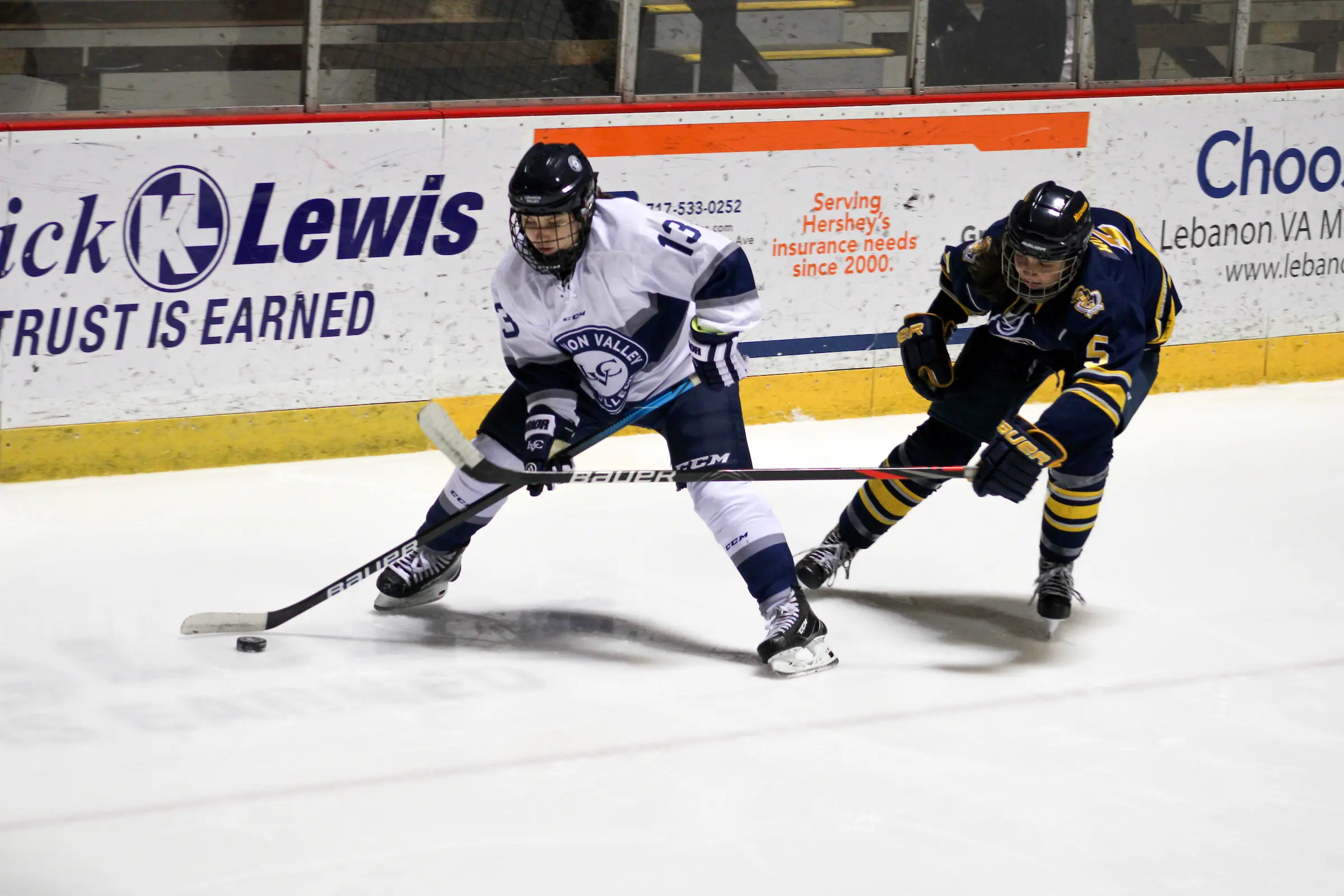 women's ice hockey player defends puck from opponent