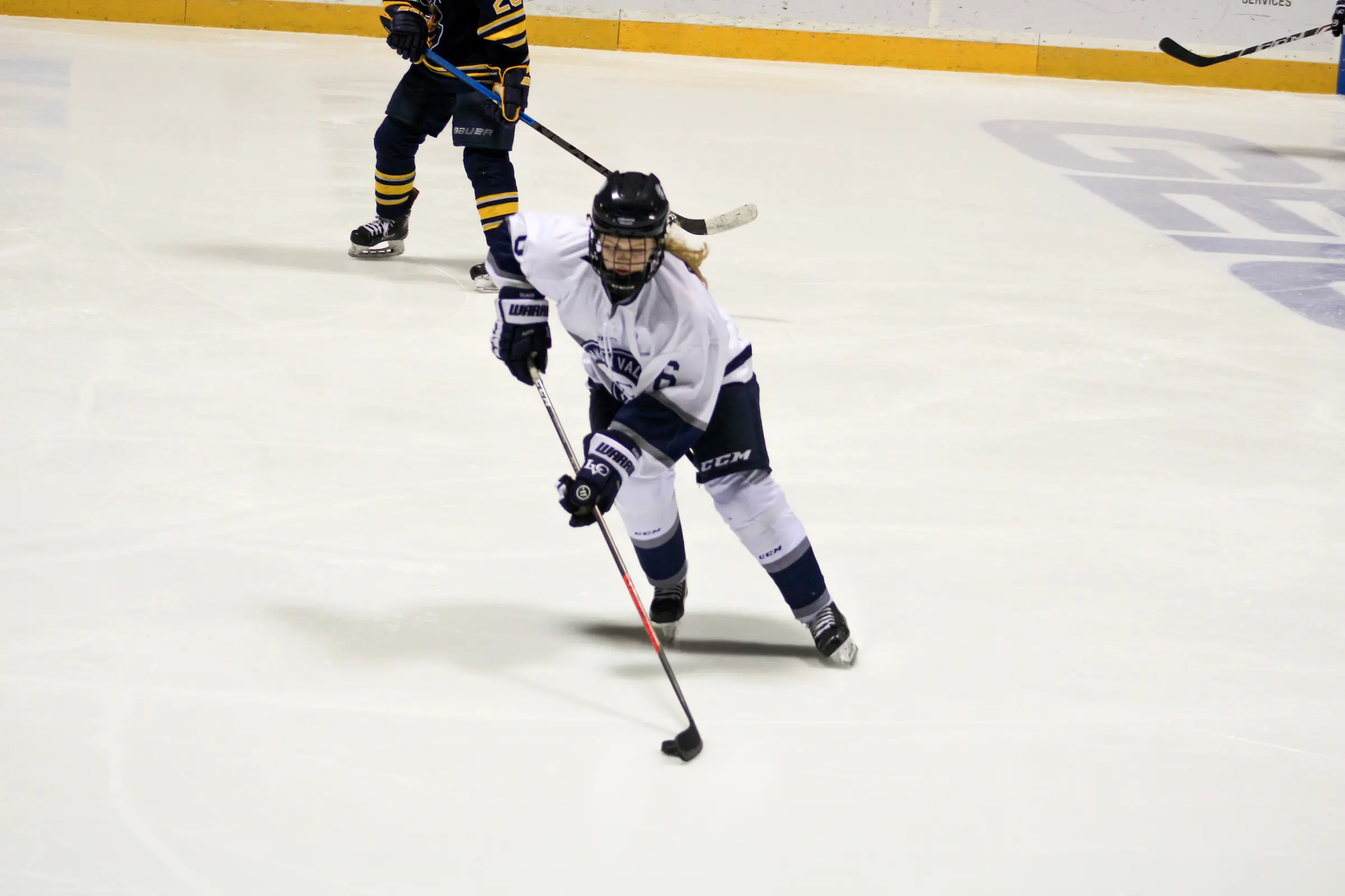 women's ice hockey player skates with puck