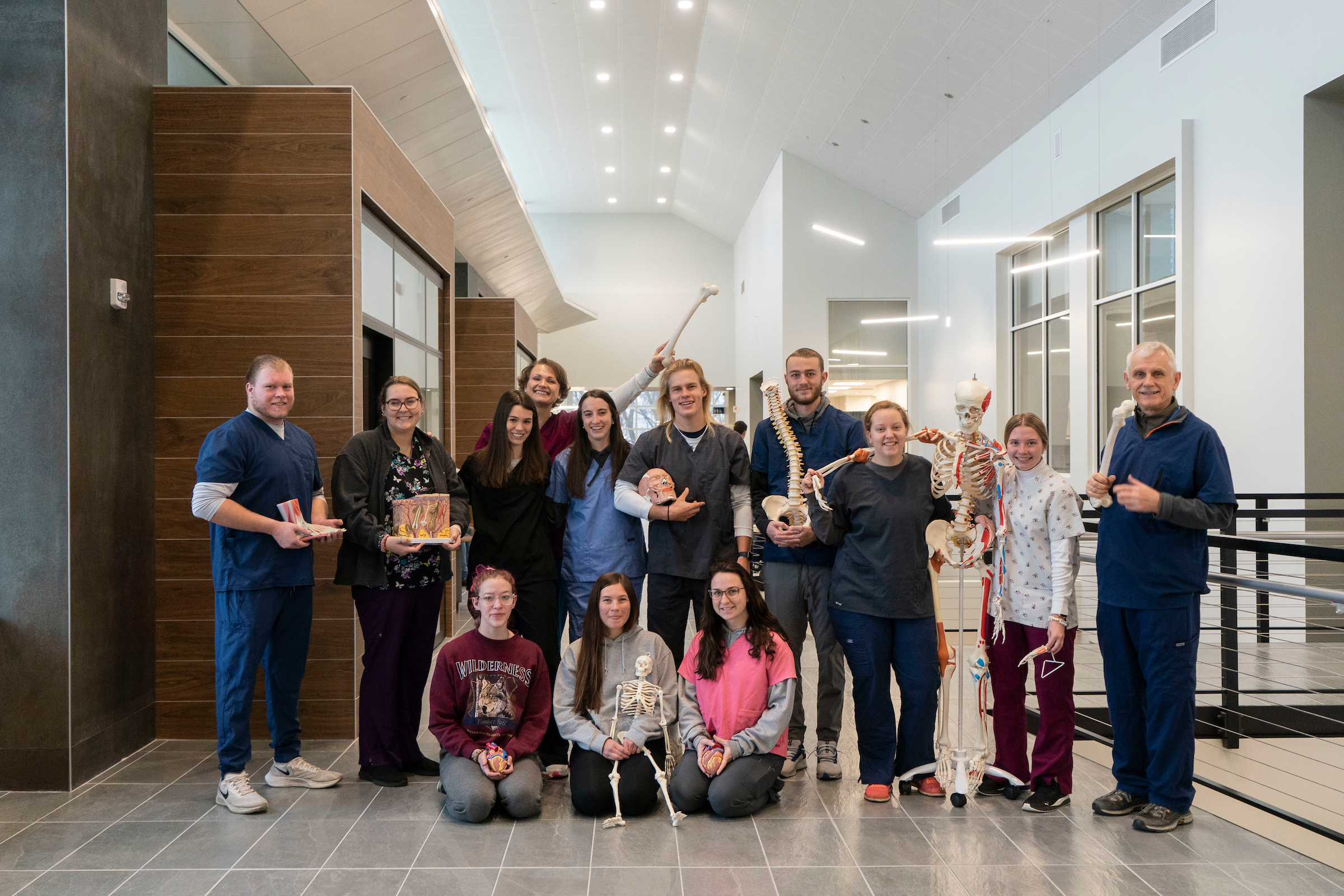 Athletic training students and faculty pose with skeletons and body models