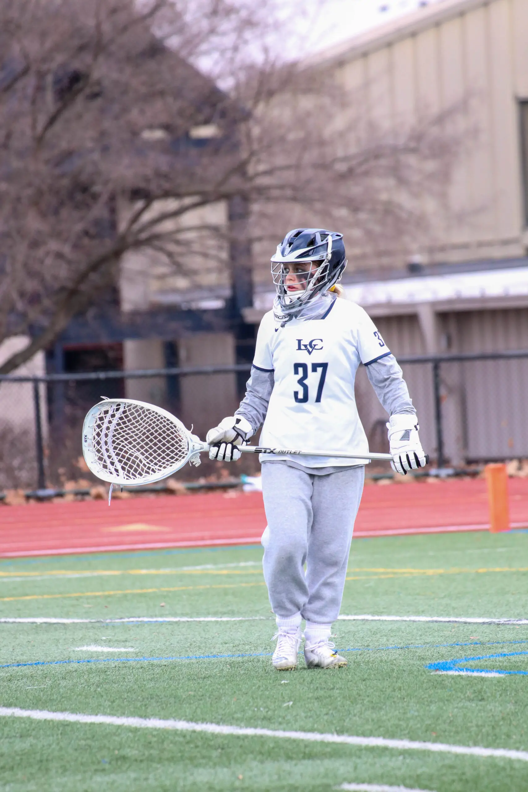 An LVC women's lacrosse player stands on the field.