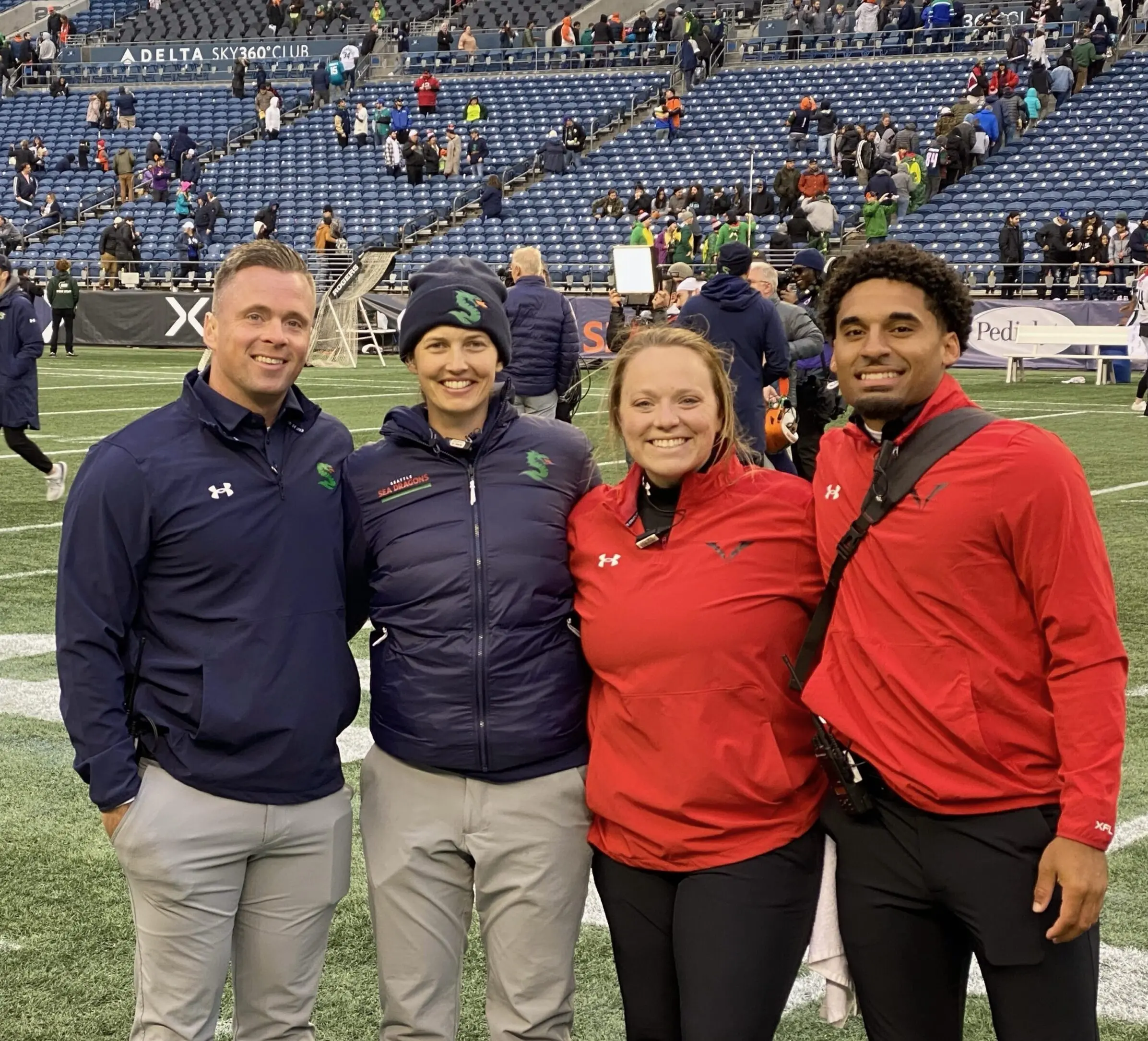 Eddie Myers IV (right) smiles on football field with fellow athletic trainers