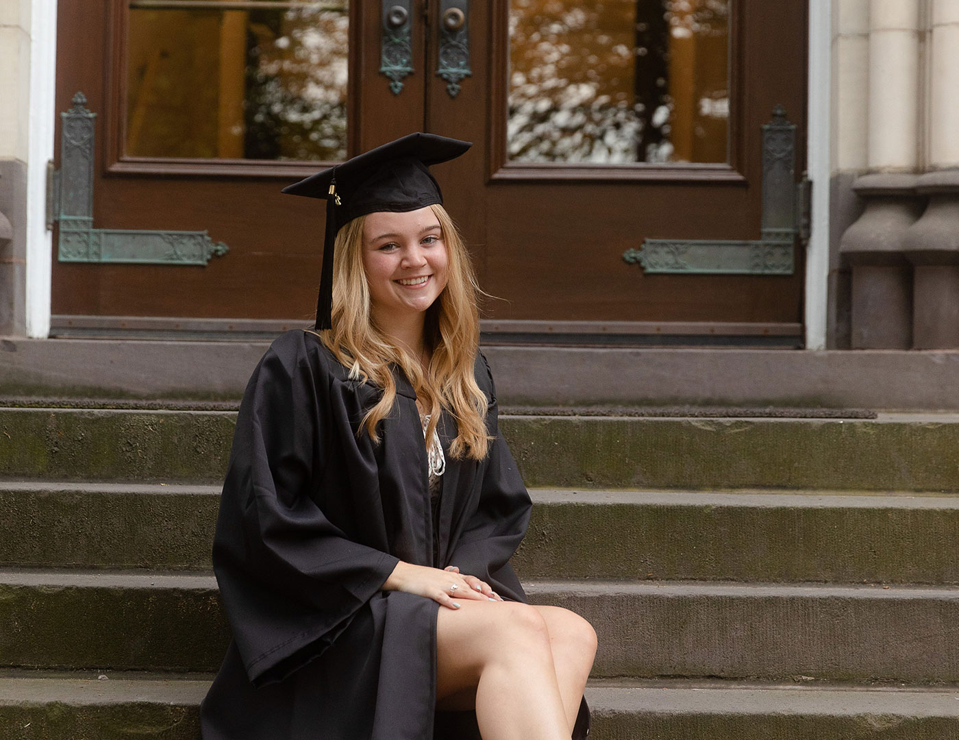 Emma Conradi sits on the steps after receiving her bachelor's degree in criminal justice