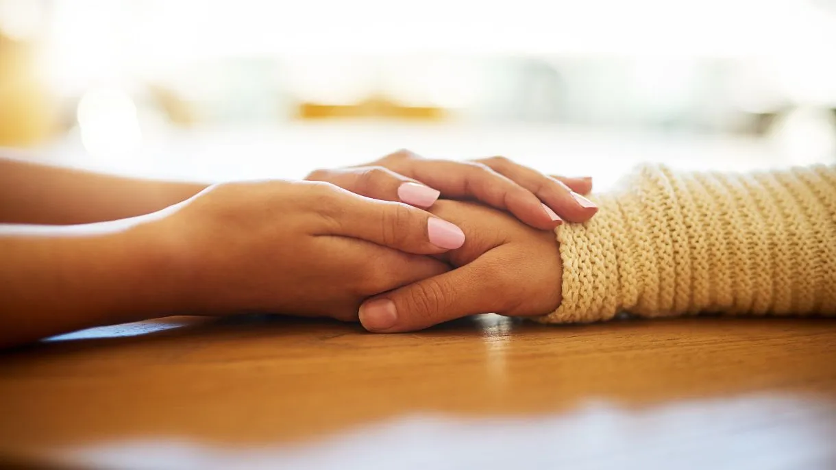 Hands held across table in supportive gesture