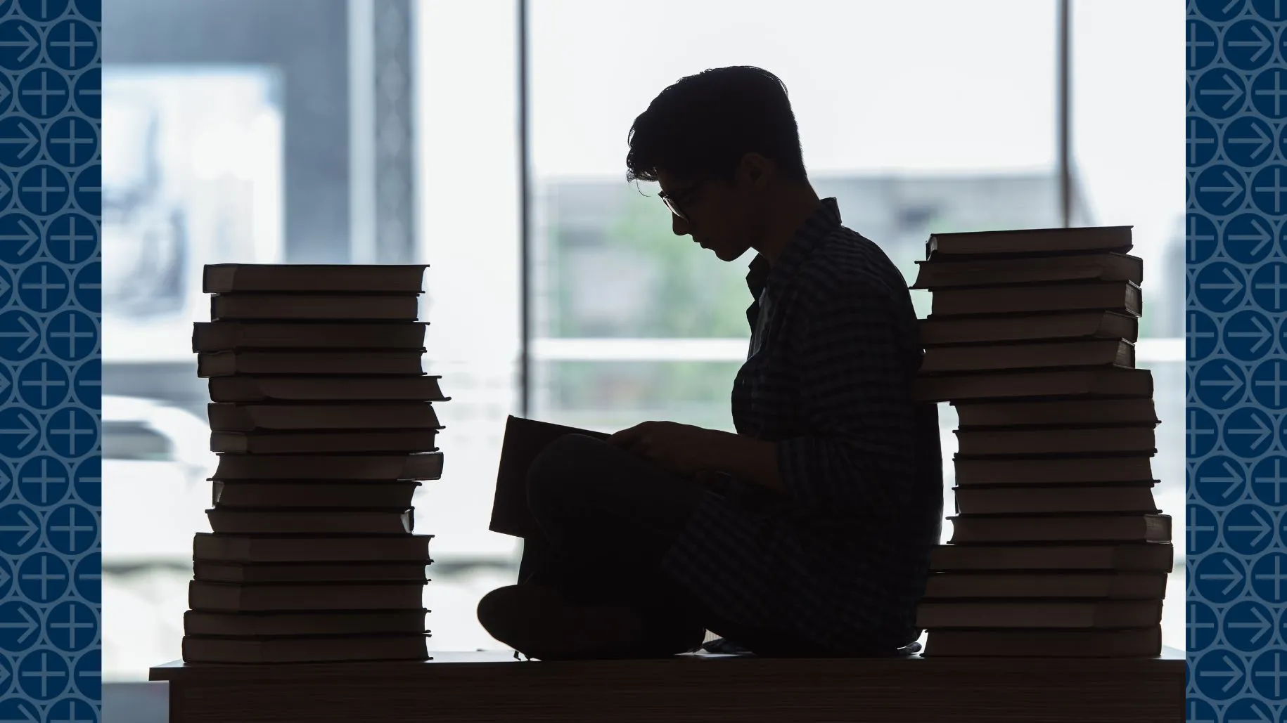 Student sits among piles of books