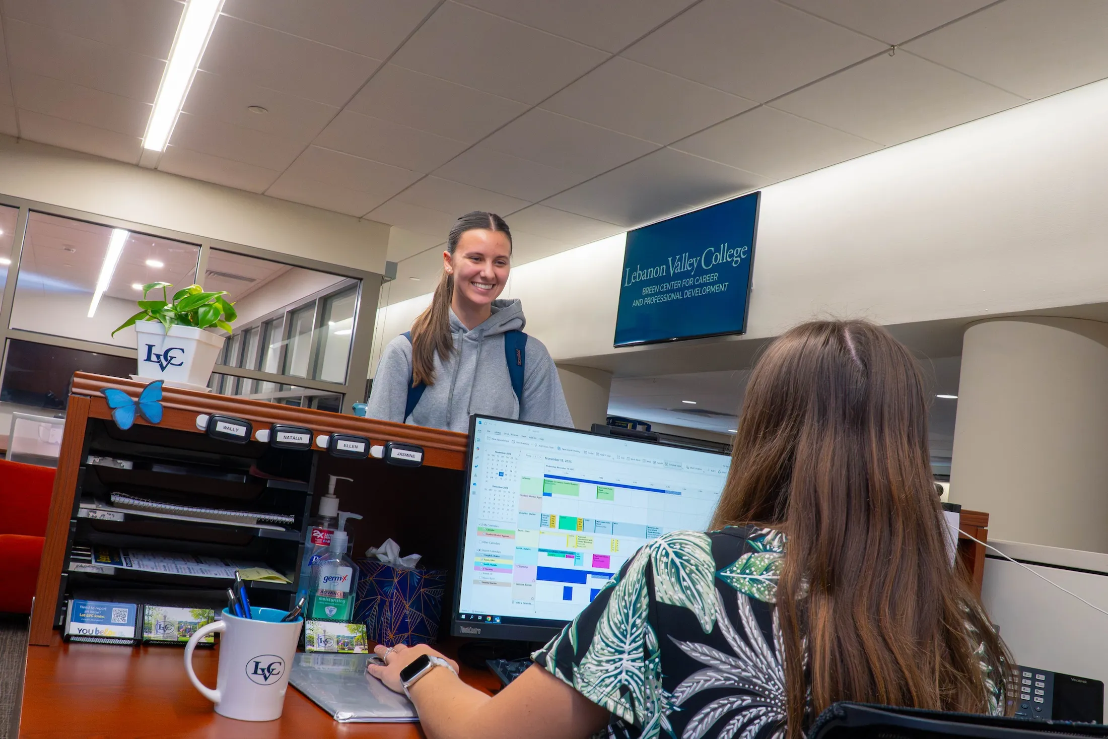 Student stands at welcome desk in Breen Center