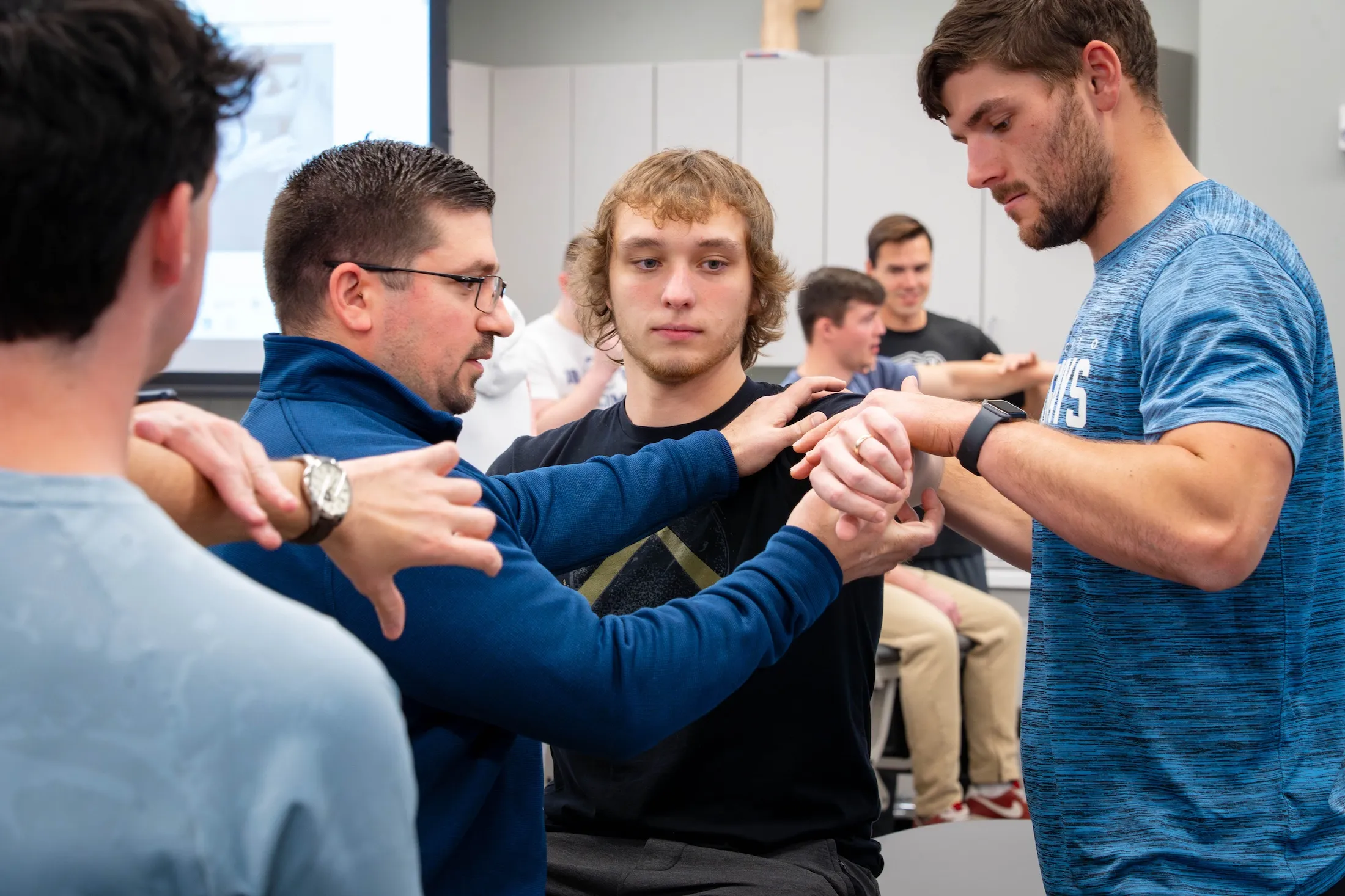 Physical Therapy instructor demonstrates on students in lab