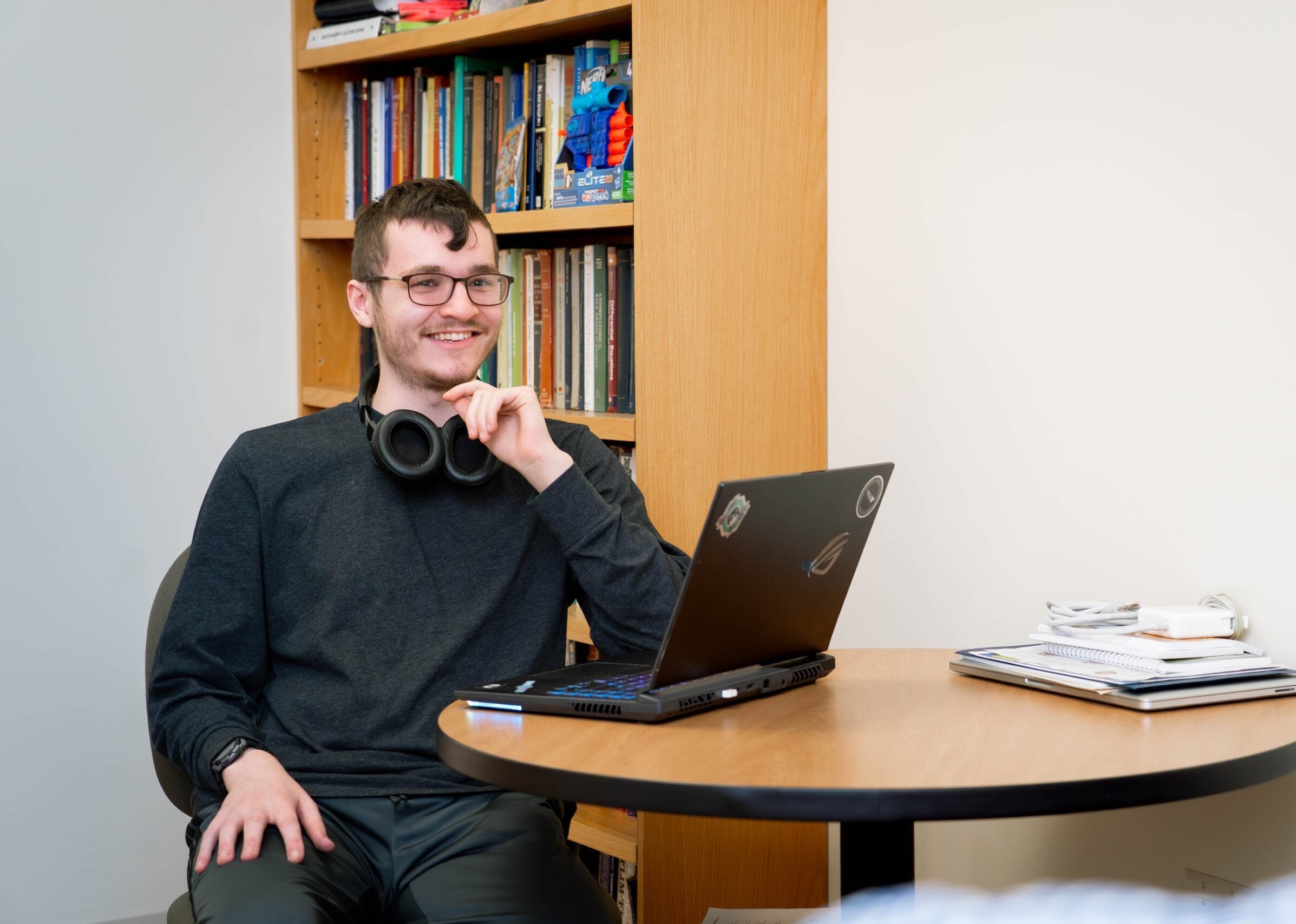 Computer science student sits at table with laptop