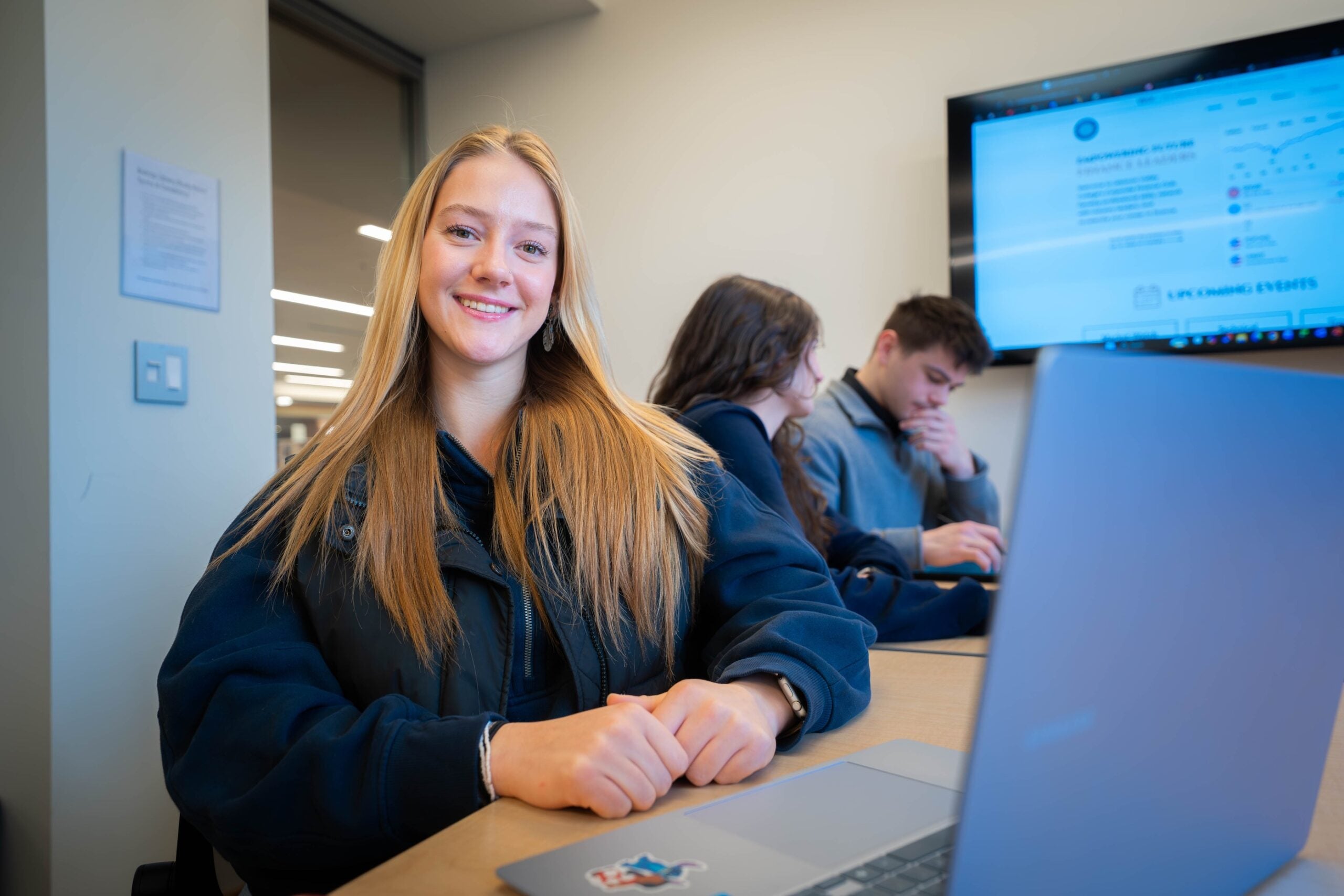Student smiles at computer in library study room