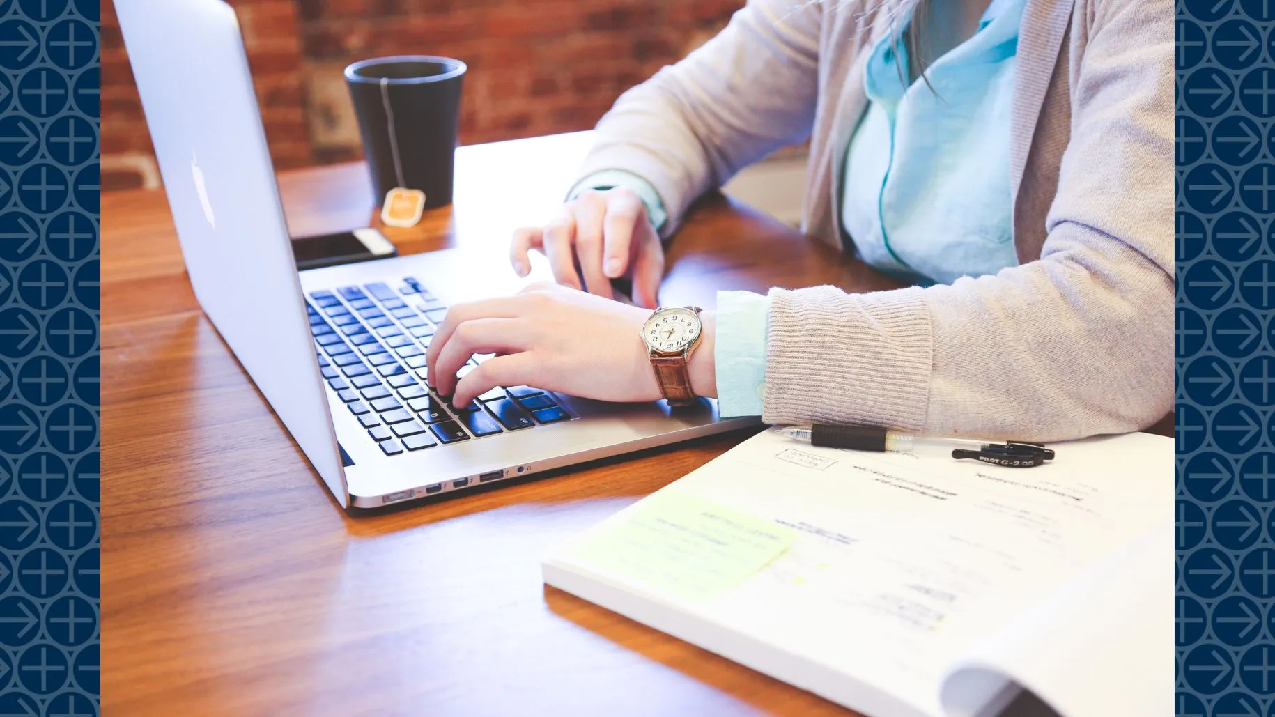 Person works on laptop with open book and tea on table