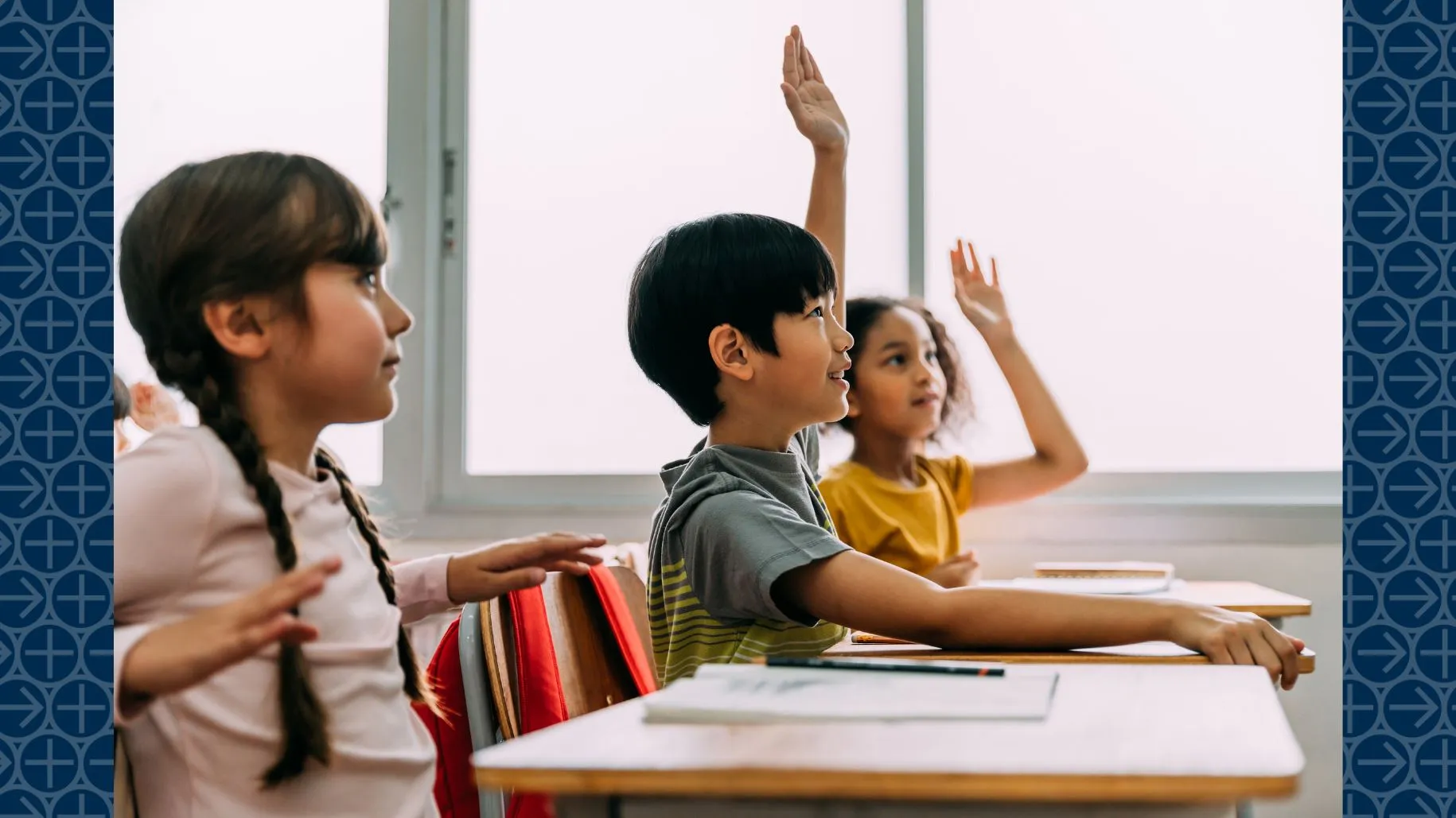 Young students raise hands in class