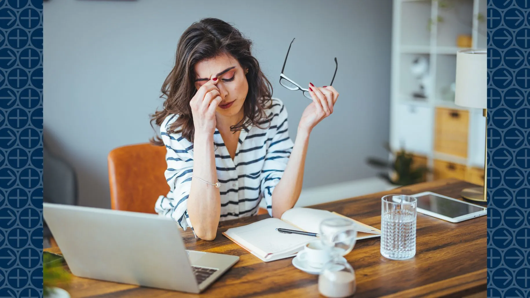 Women looks stressed sitting at desk with laptop and notebook