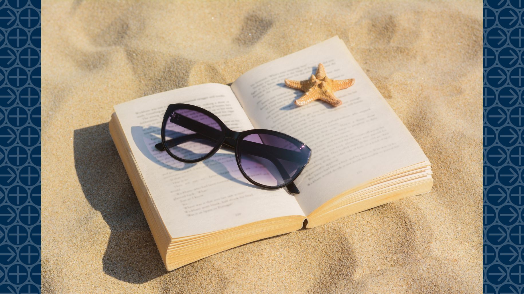 Book lies open on sand with sunglasses and starfish on pages