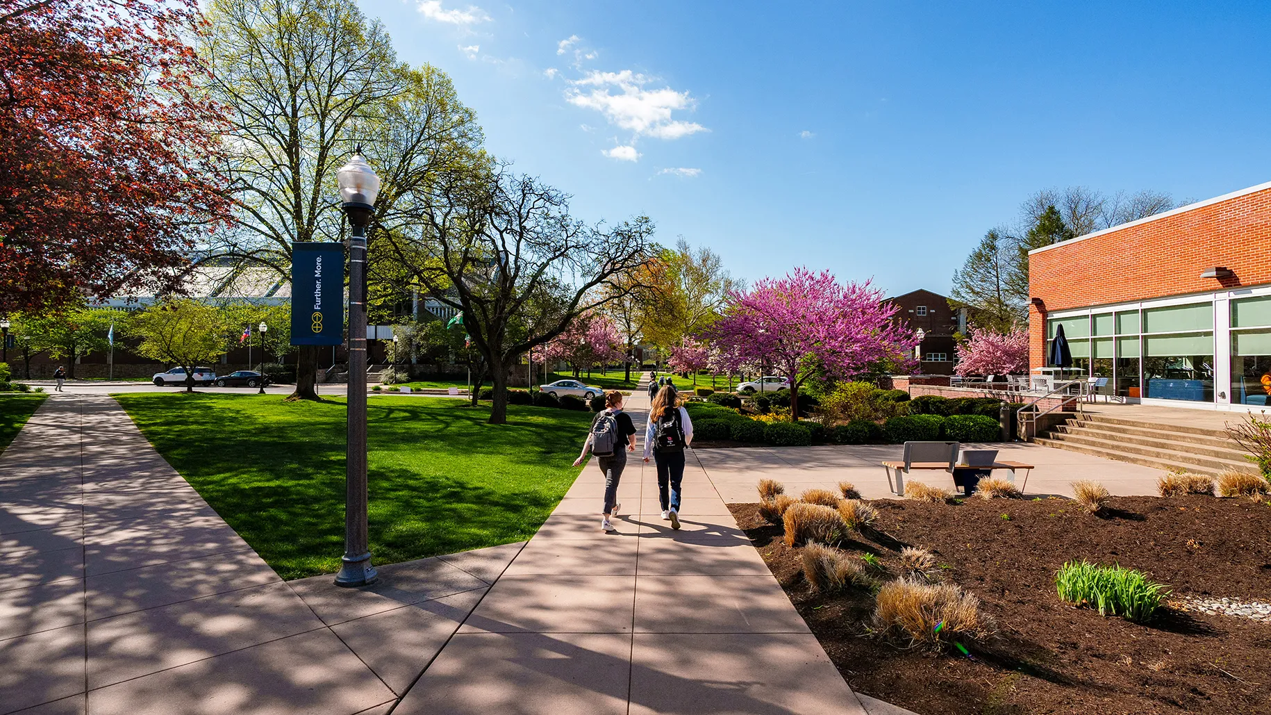 Students walk along the sidewalk of Mund College Center