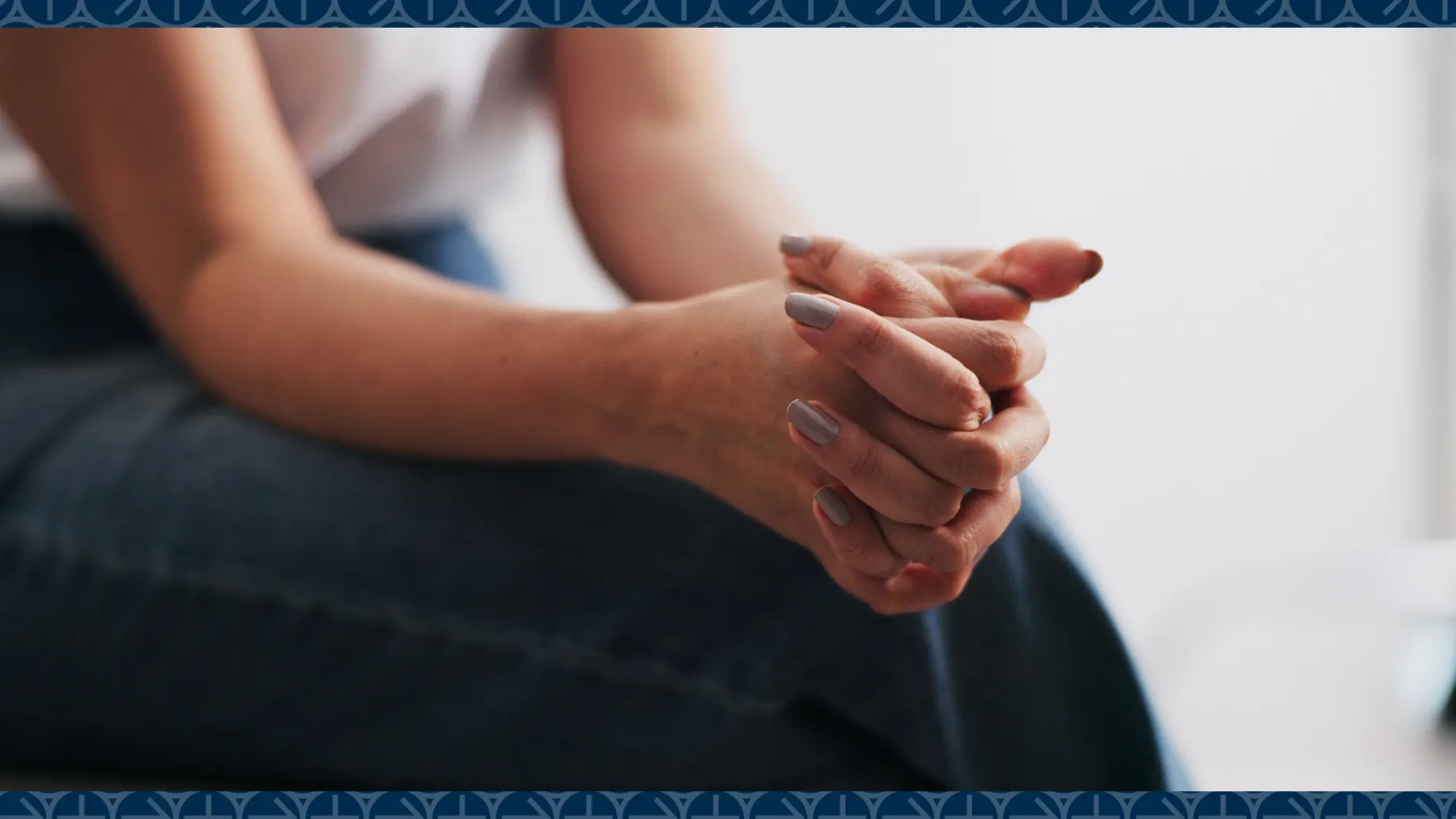 Person sits with hands clasped on leg